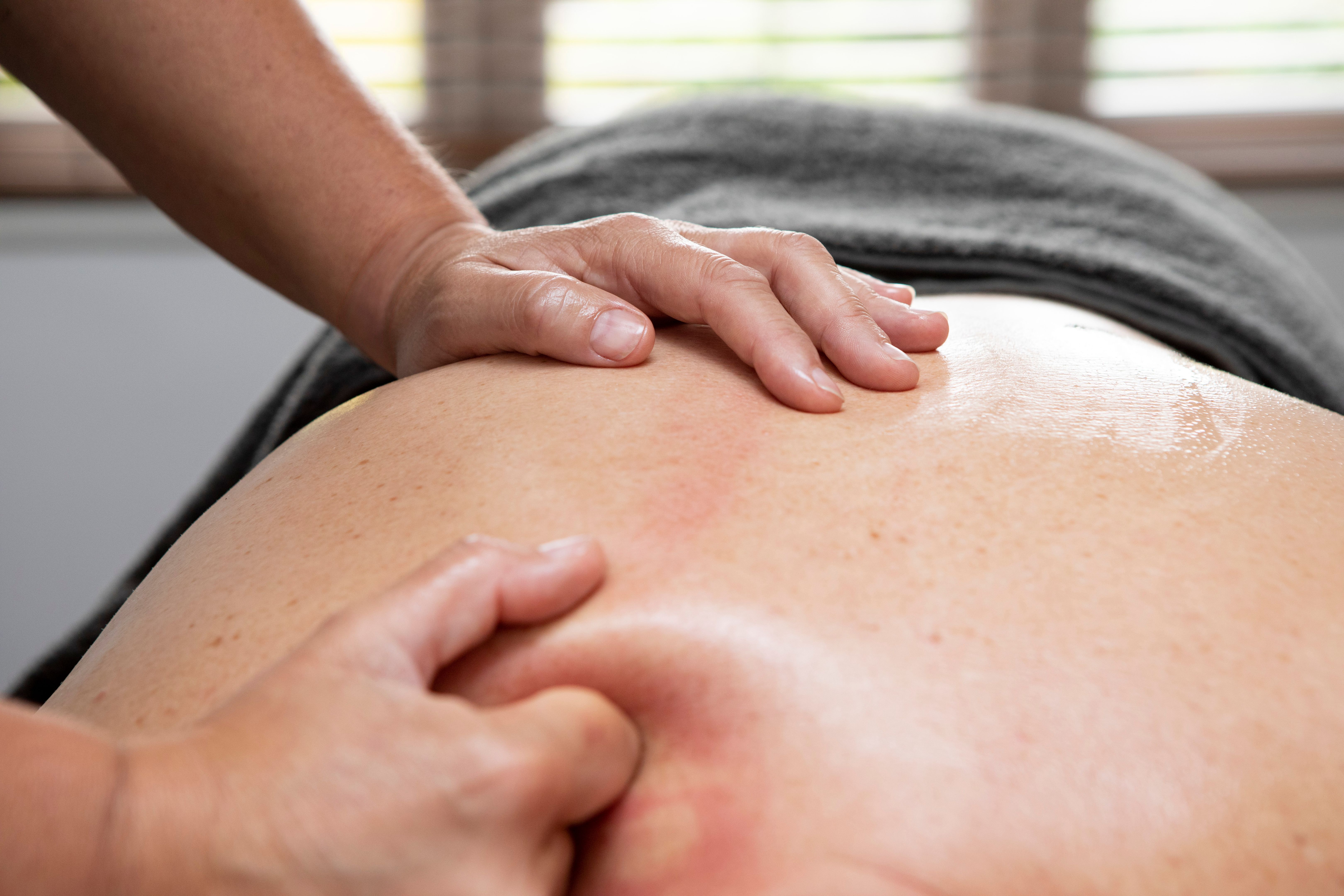 Close-up of female hands giving a deep tissue massage to a man lying face down