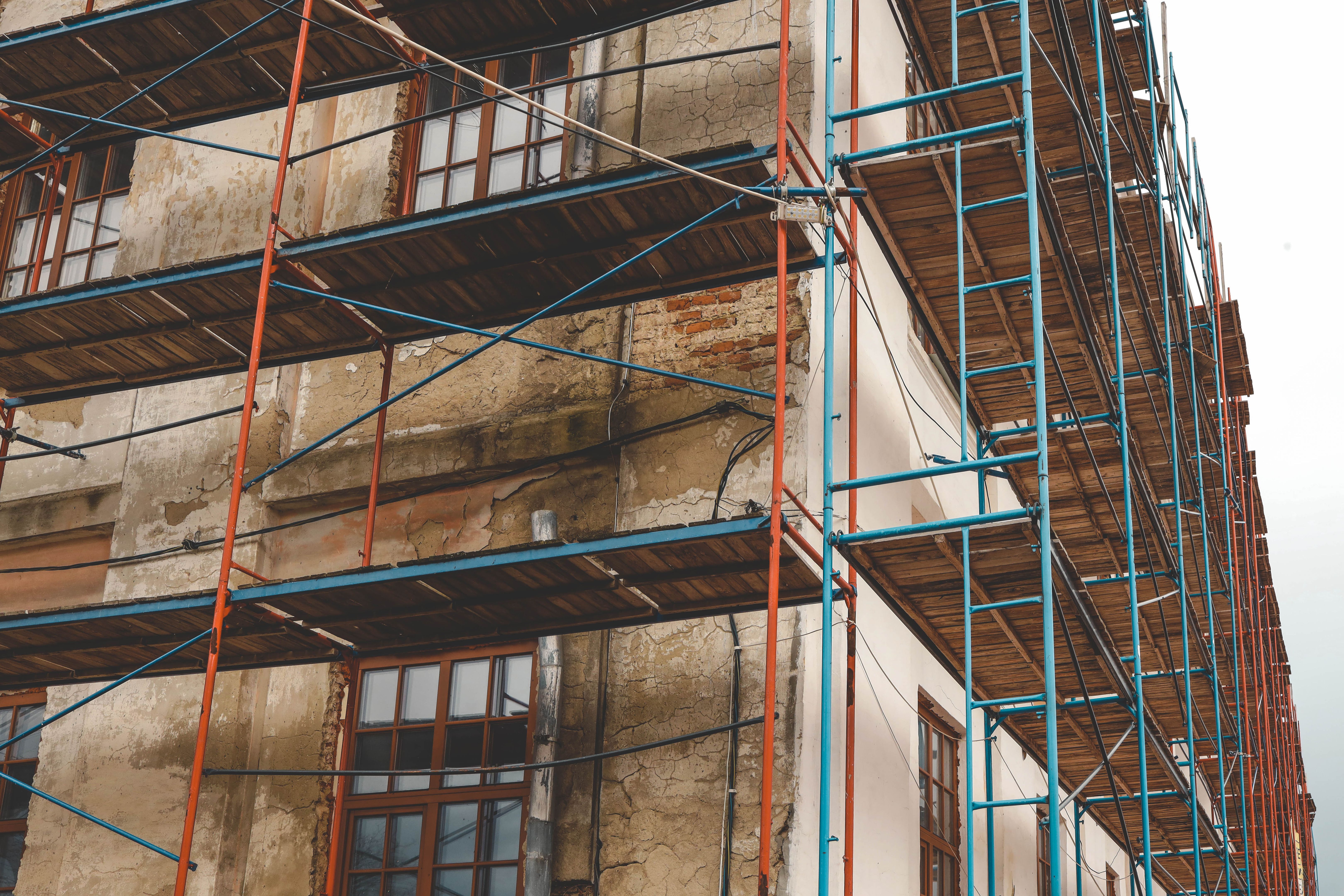 Scaffolding on a generic old tenement house, renovated historical building facade detail, closeup, nobody. Restoration industry, old architecture, real estate renovation simple concept, no people