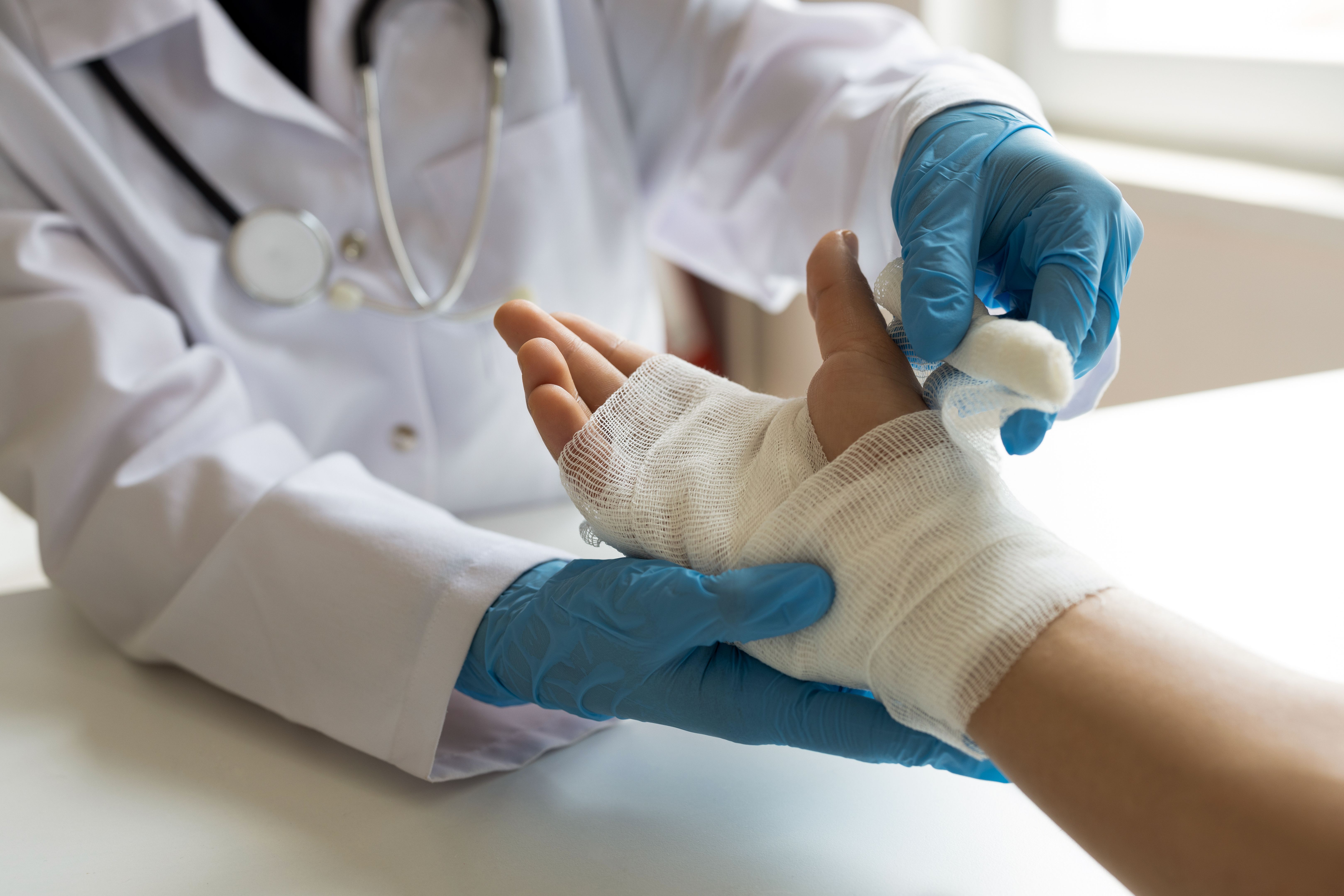 Doctor wrapping patient's hands with bandage