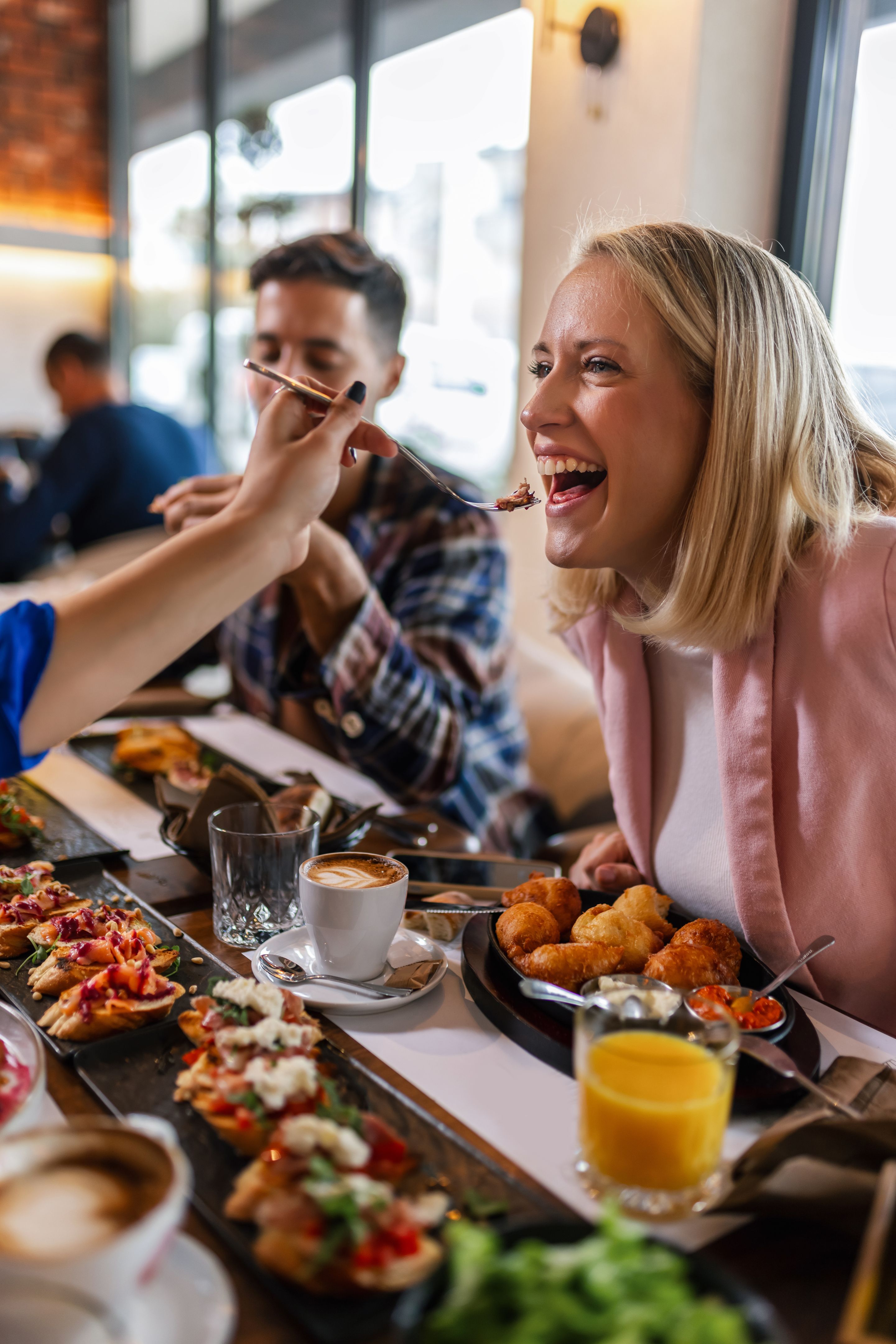 Friends feeding eachother with delicious food in a restaurant. Friends feeding eachother with delicious food in a restaurant.