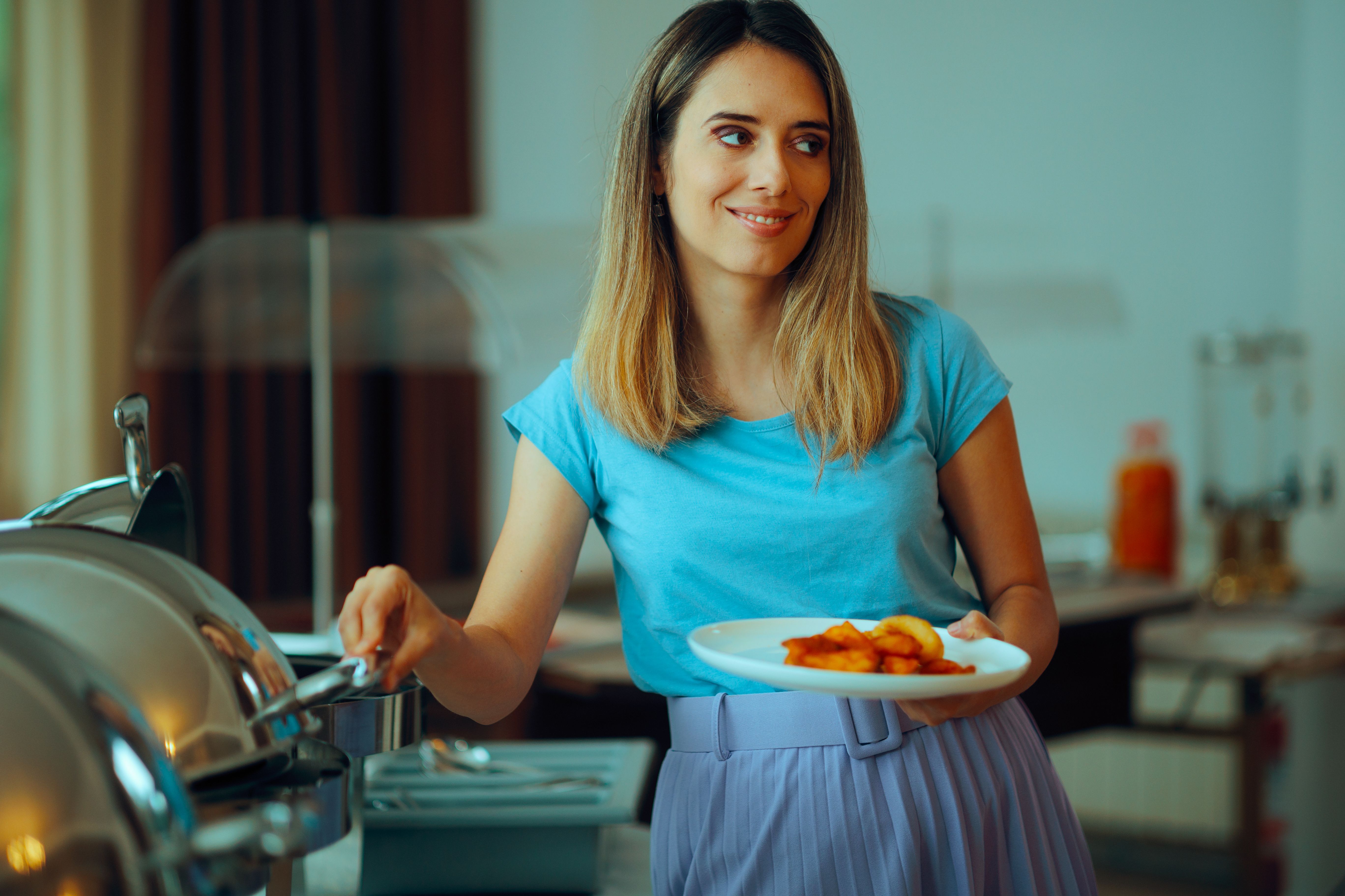 Woman Taking Breakfast Foods from a Hotel Buffet Woman Taking Breakfast Foods from a Hotel Buffet