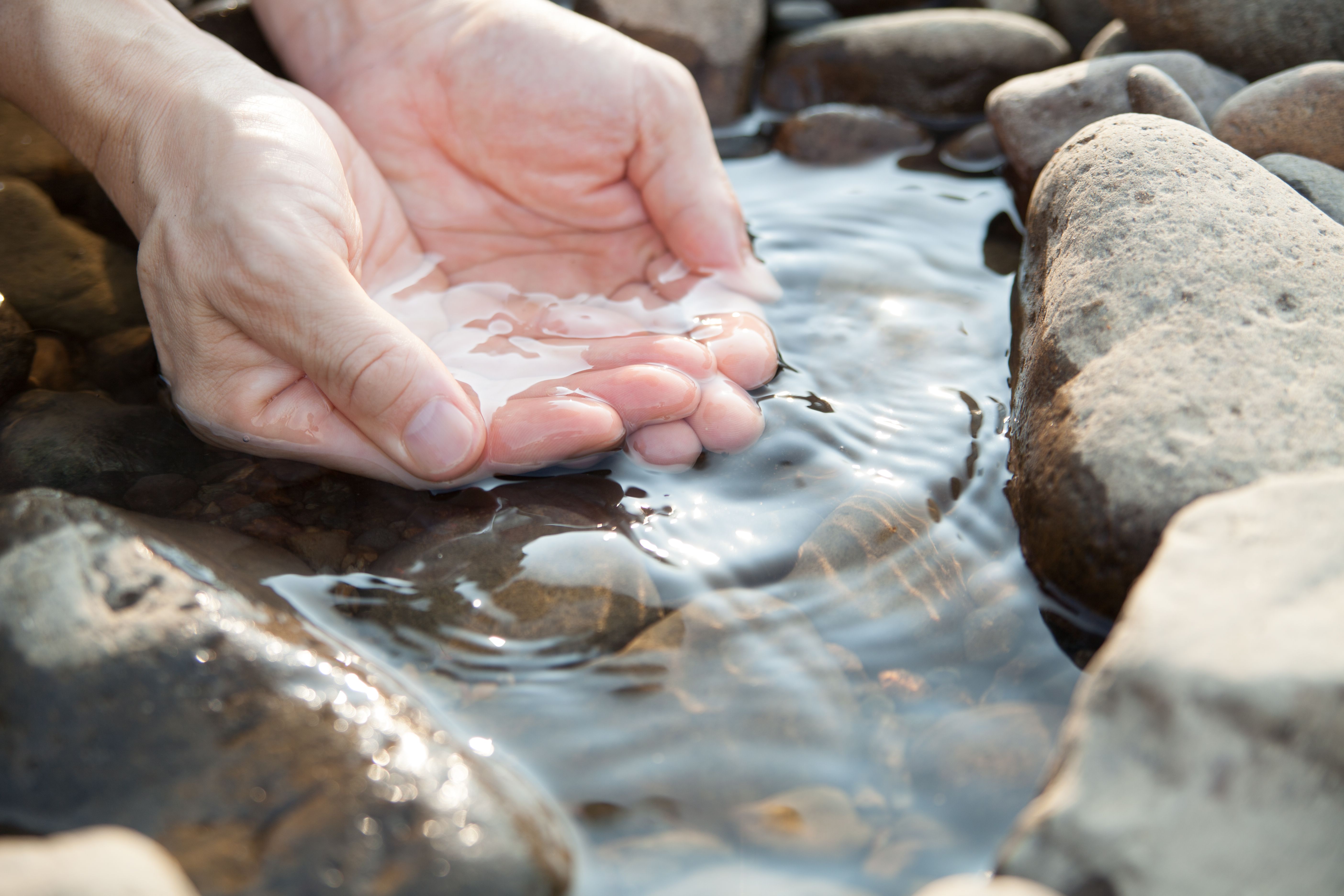 hands touching the body of water