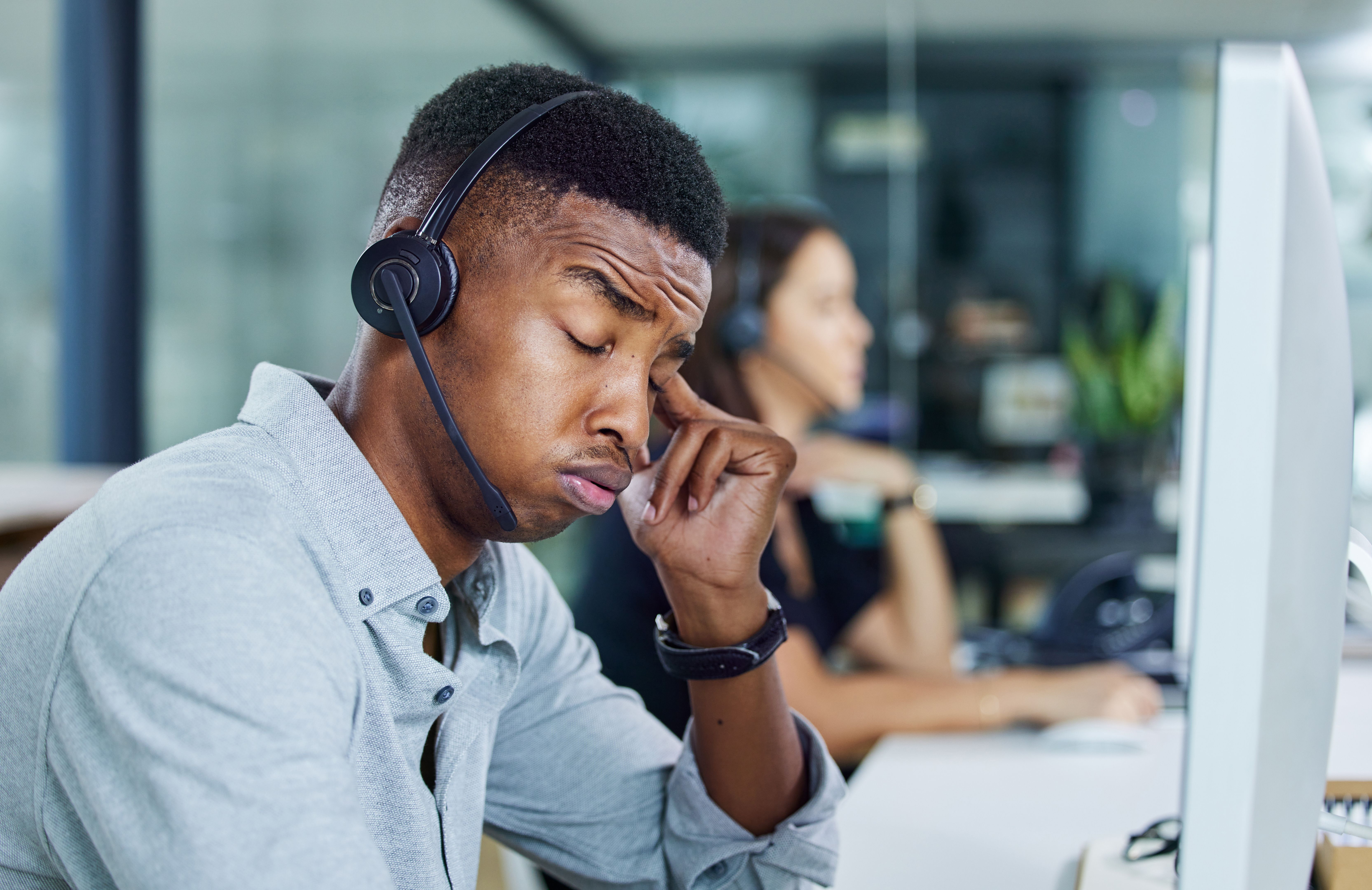 Shot of a young call centre agent looking tired in an office