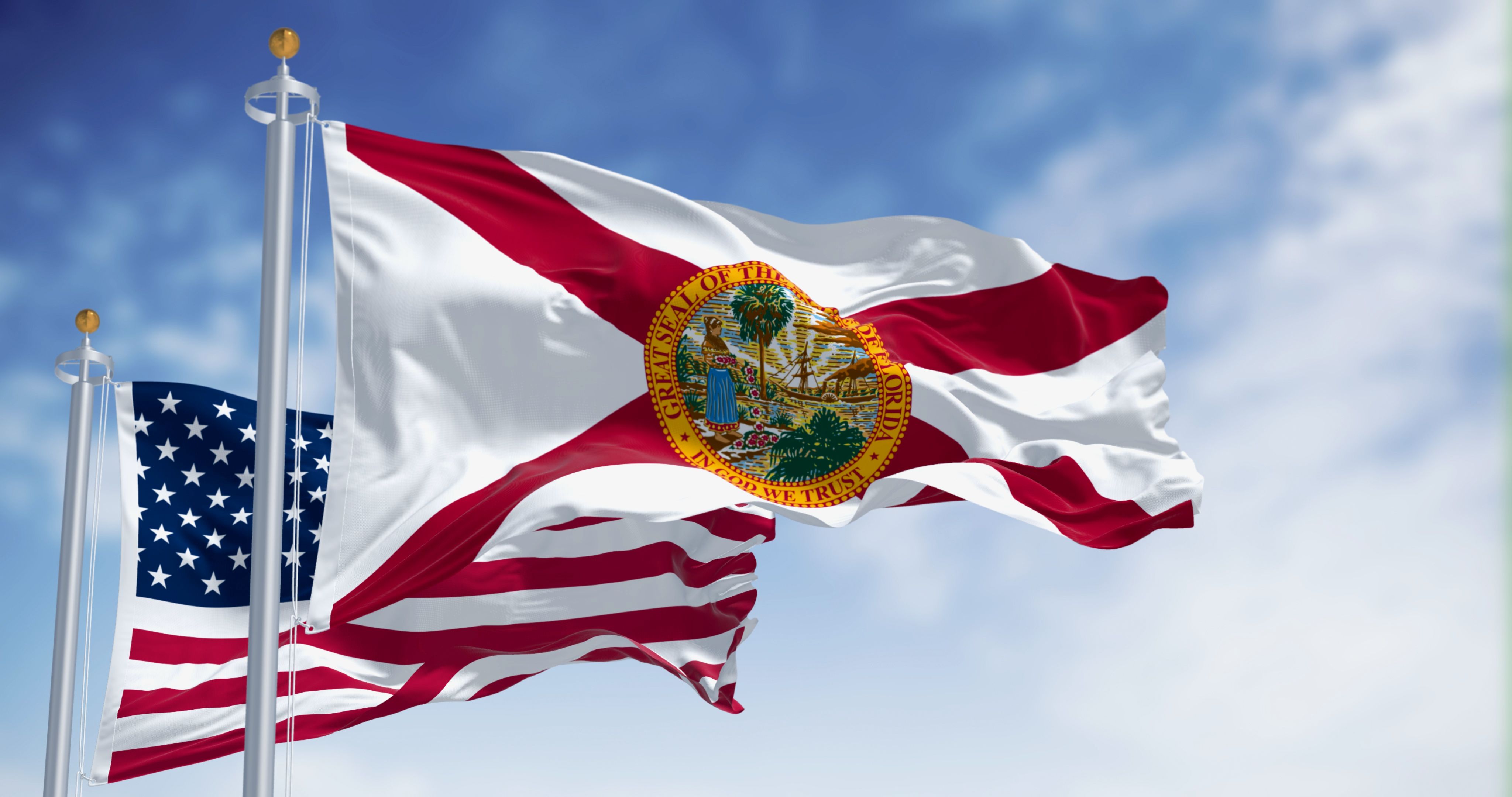 Flags of Florida and United States waving in the wind on a clear day
