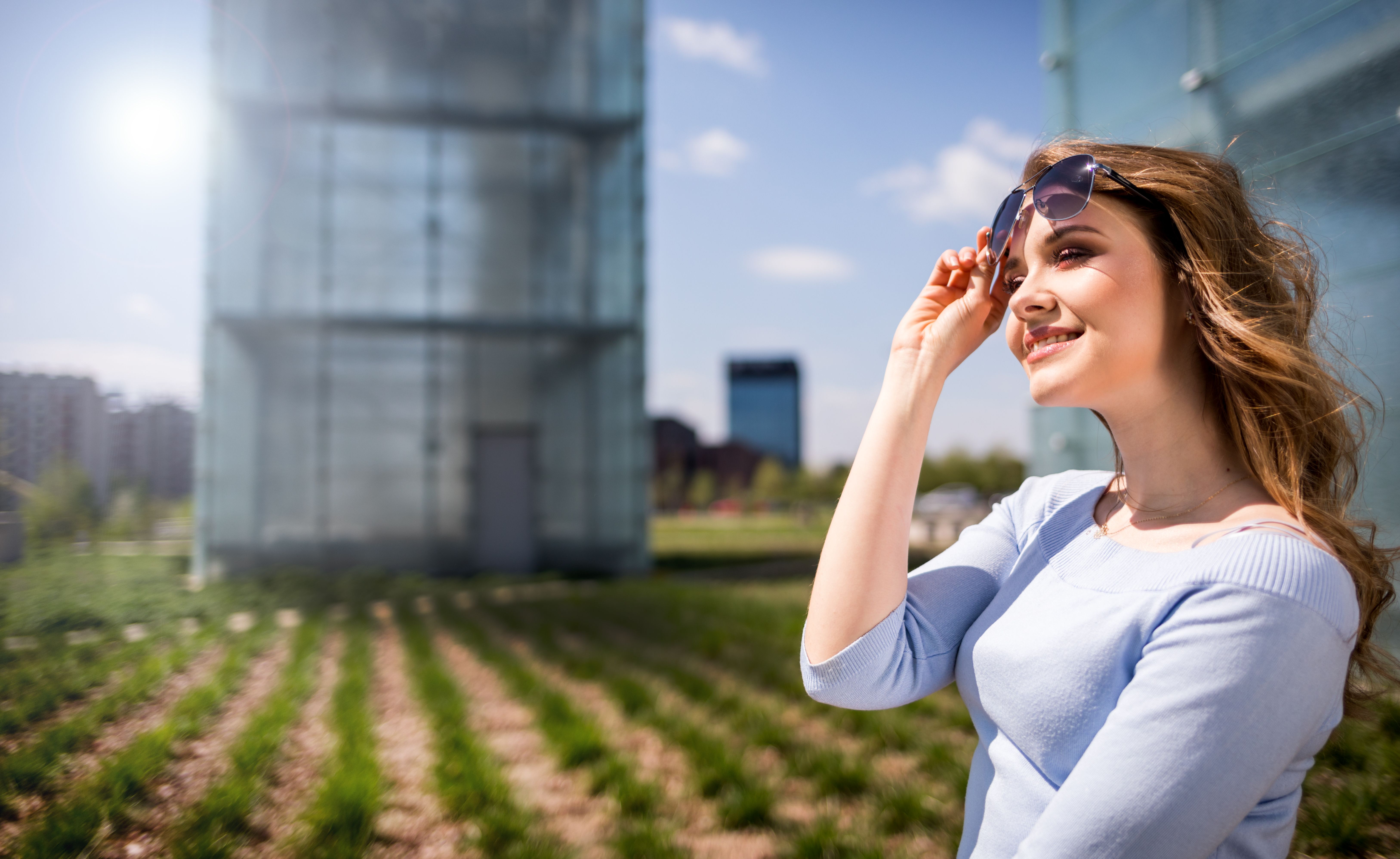 Elegant young woman walking around modern buildings and green city garden on street Elegant young woman walking around modern buildings and green city garden on street