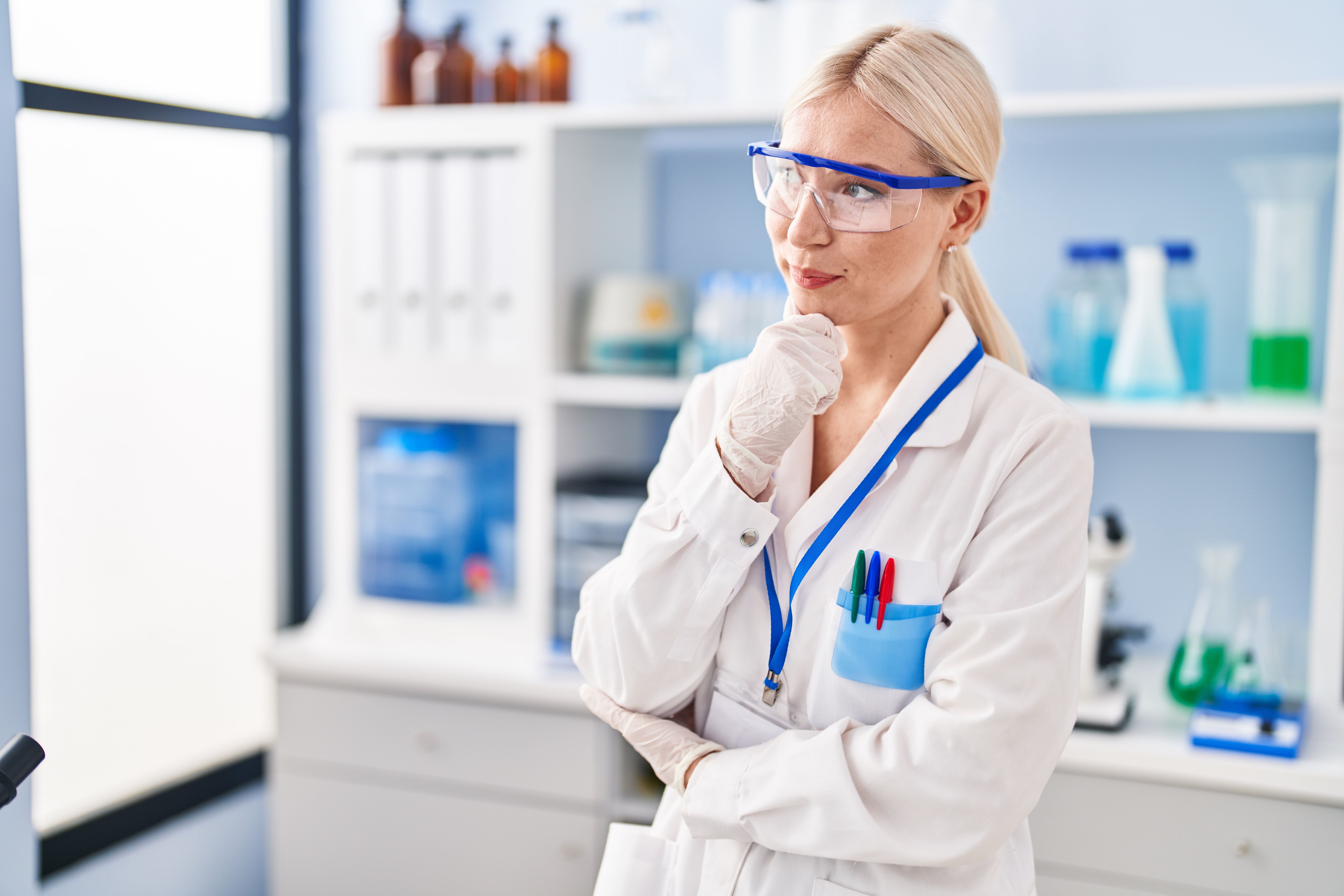 Young blonde woman wearing scientist uniform standing at laboratory Young blonde woman wearing scientist uniform standing at laboratory