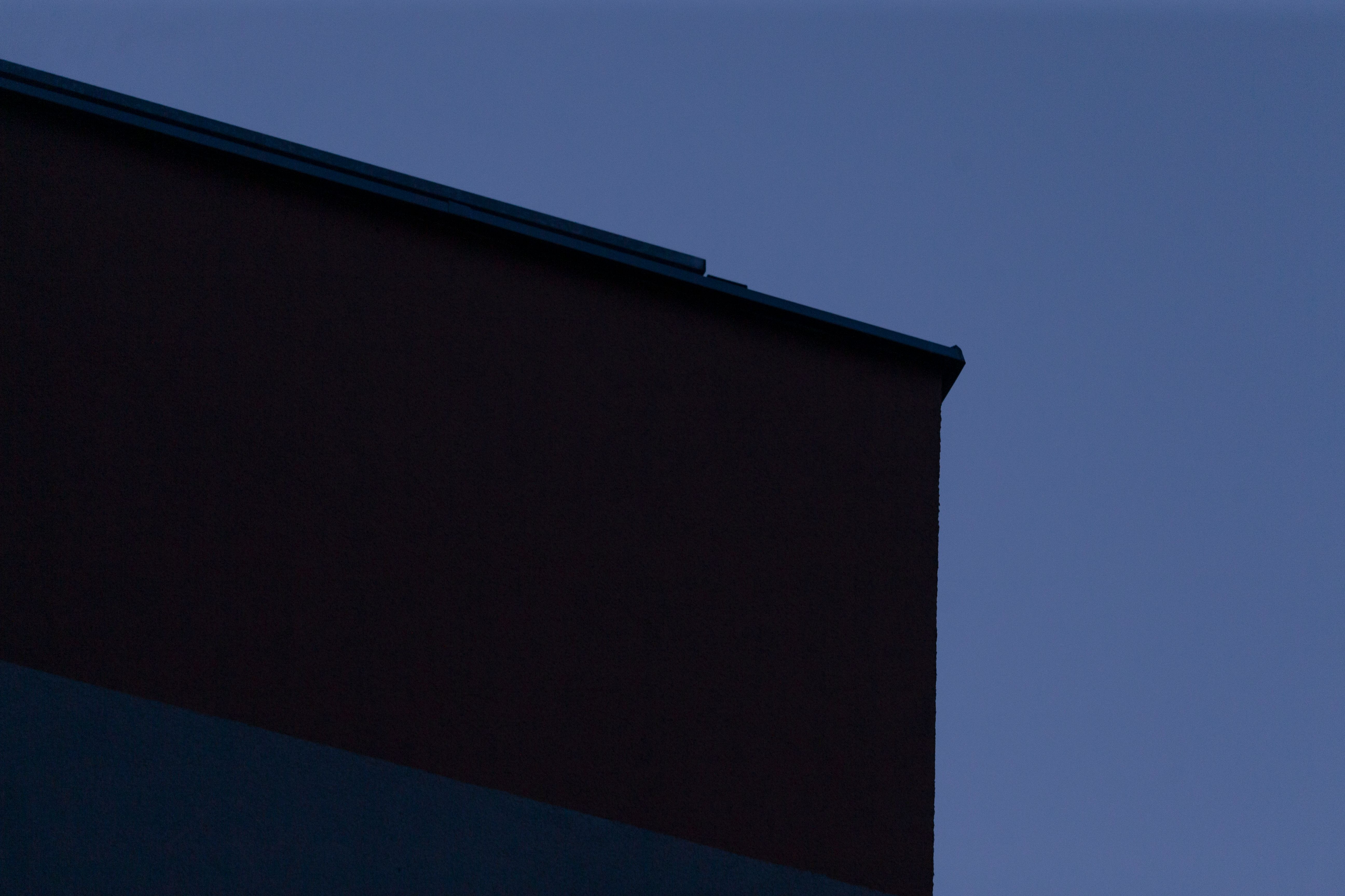 A dark building stands tall against a beautiful blue sky background