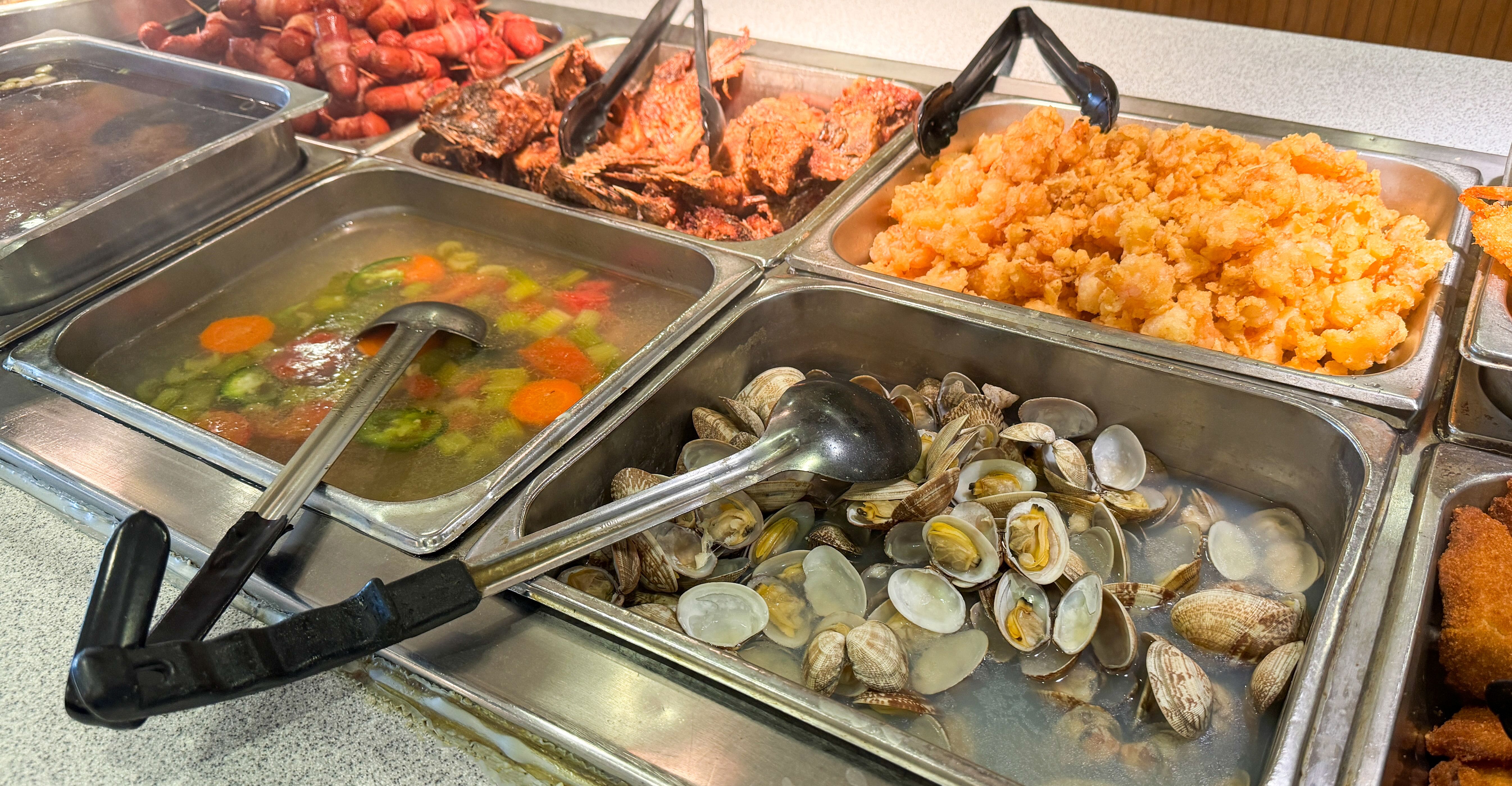 A buffet selection featuring a variety of seafood, fried food, and vegetable soup A buffet selection featuring a variety of seafood, fried food, and vegetable soup