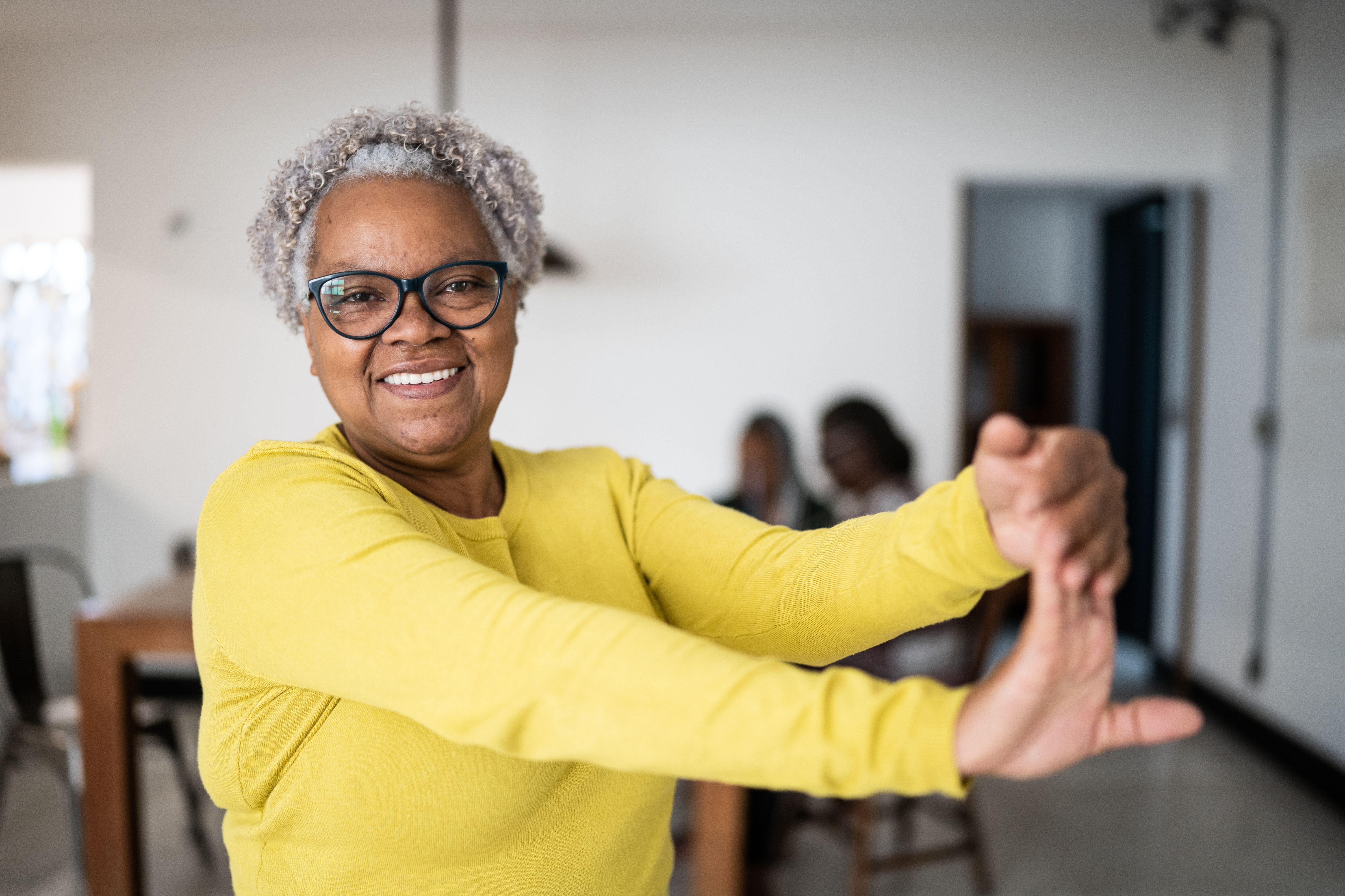 Portrait of a senior woman stretching her arms at home