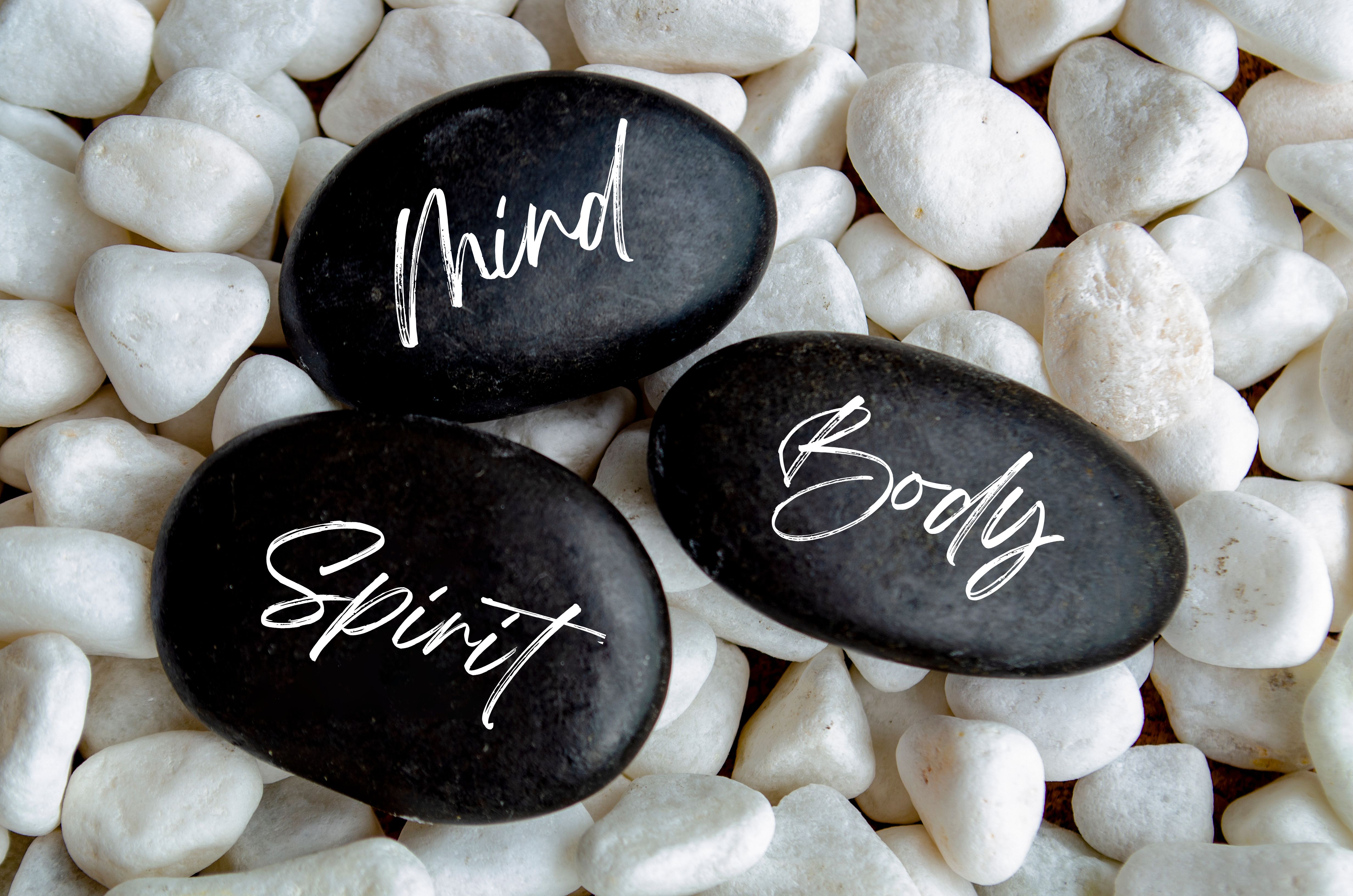 Top view of mind, body spirit text on black zen stones