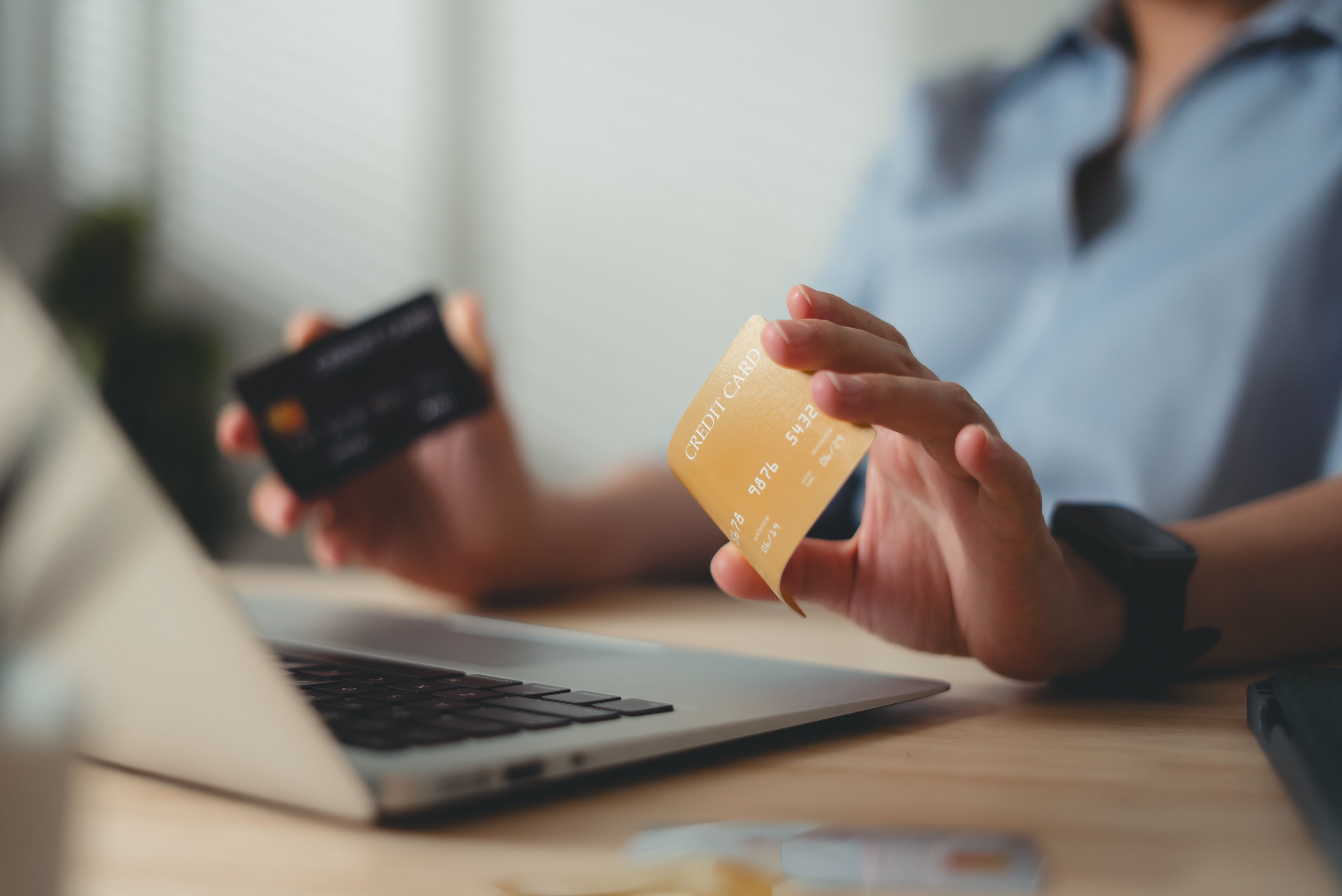 Close-up shot of female hand bending credit card on table at home office.