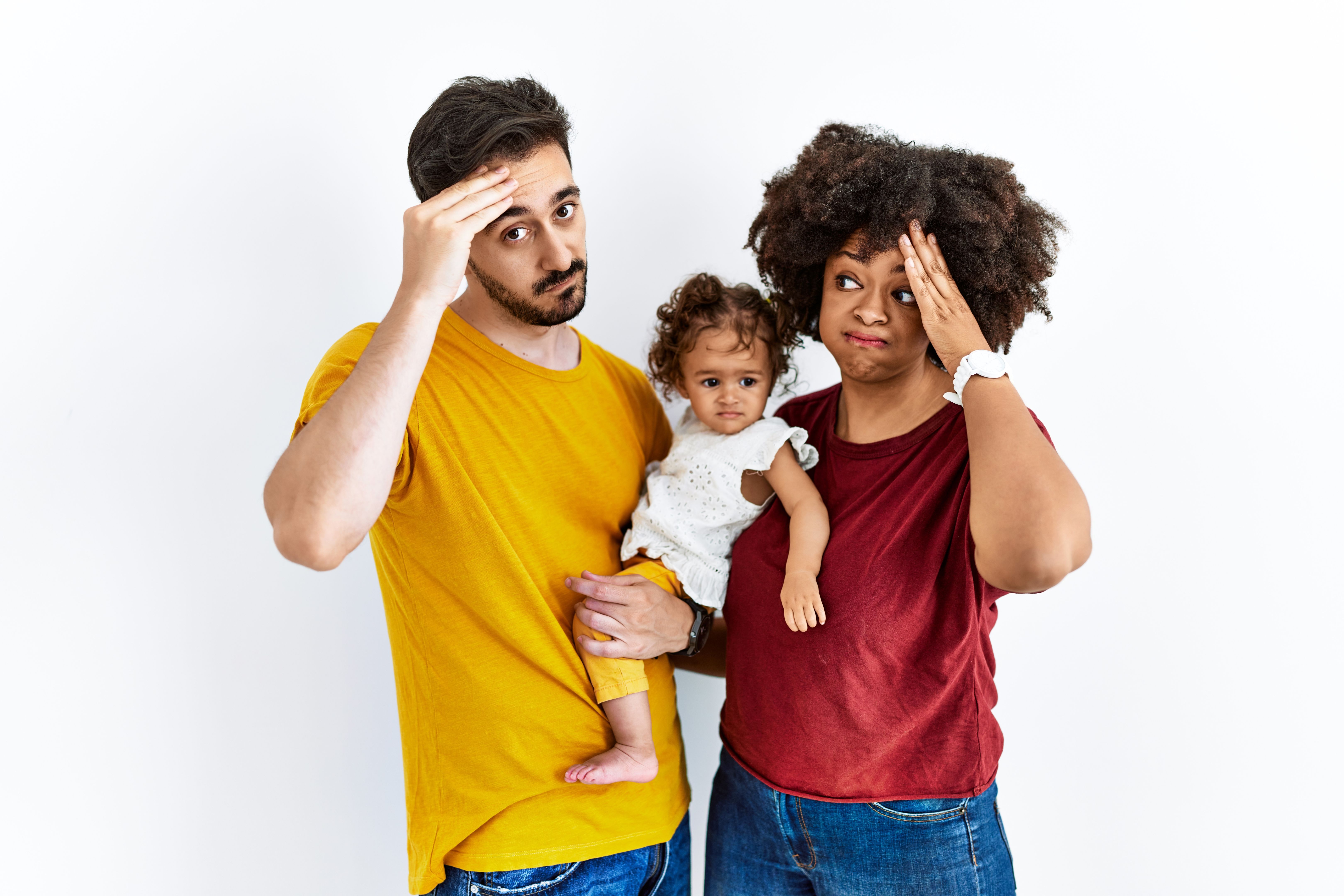 Interracial young family of black mother and hispanic father with daughter worried and stressed about a problem with hand on forehead, nervous and anxious for crisis