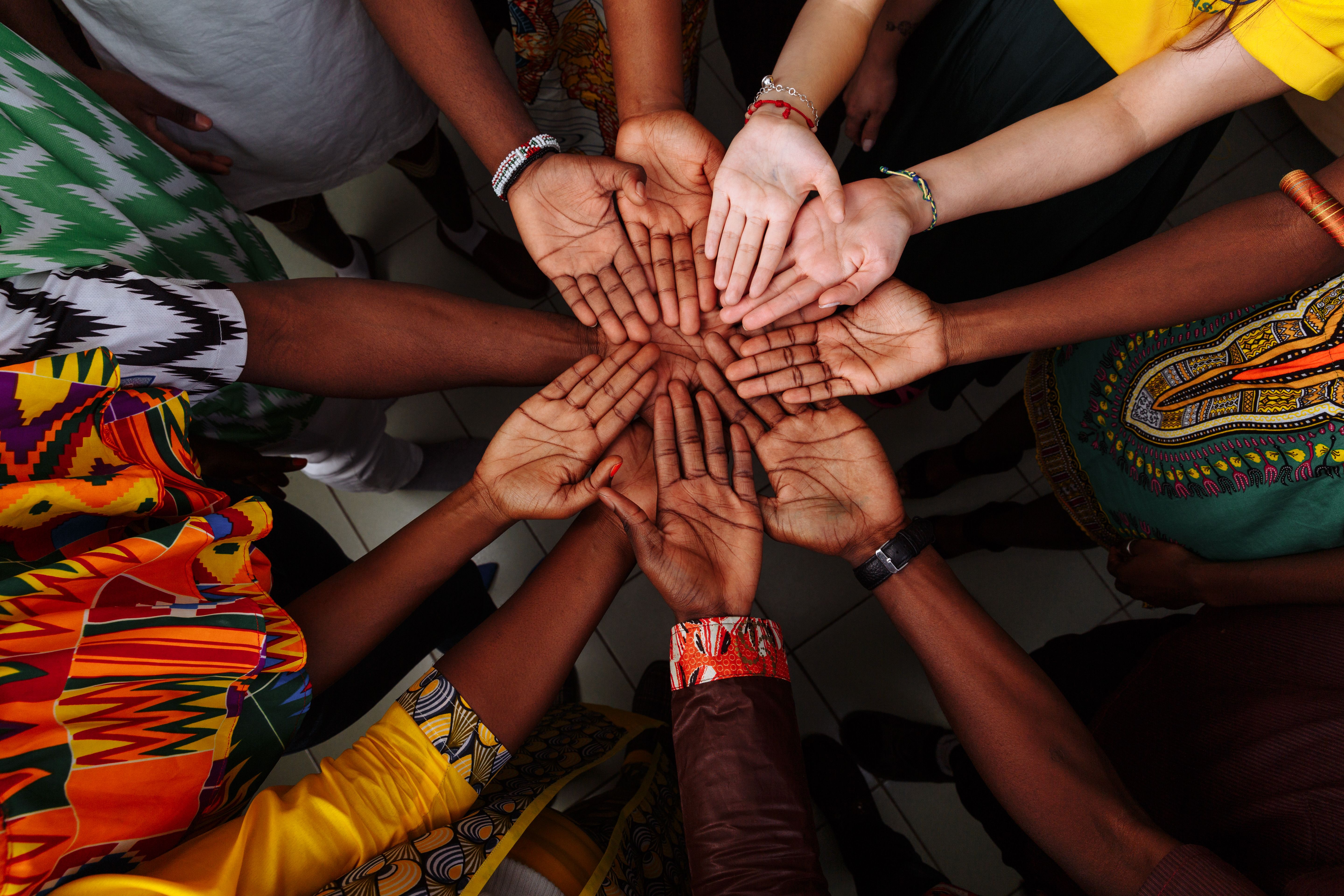 Palms up hands of a group of multinational people: African, Latin American and European people which stay together in a circle