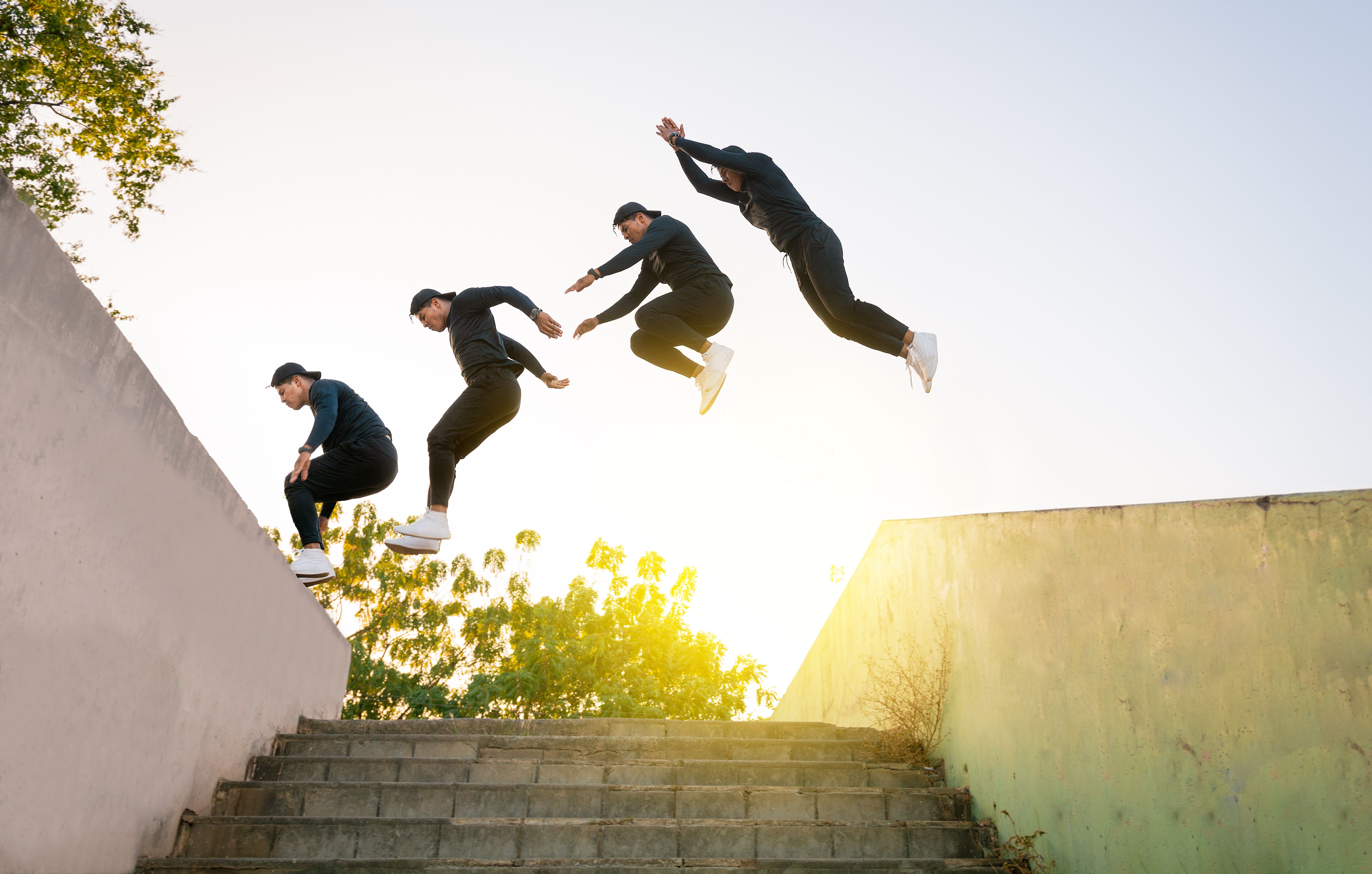 Athlete man doing parkour jumping walls. Low angle of man doing parkour at sunset. Latin guy doing parkour jumping walls.