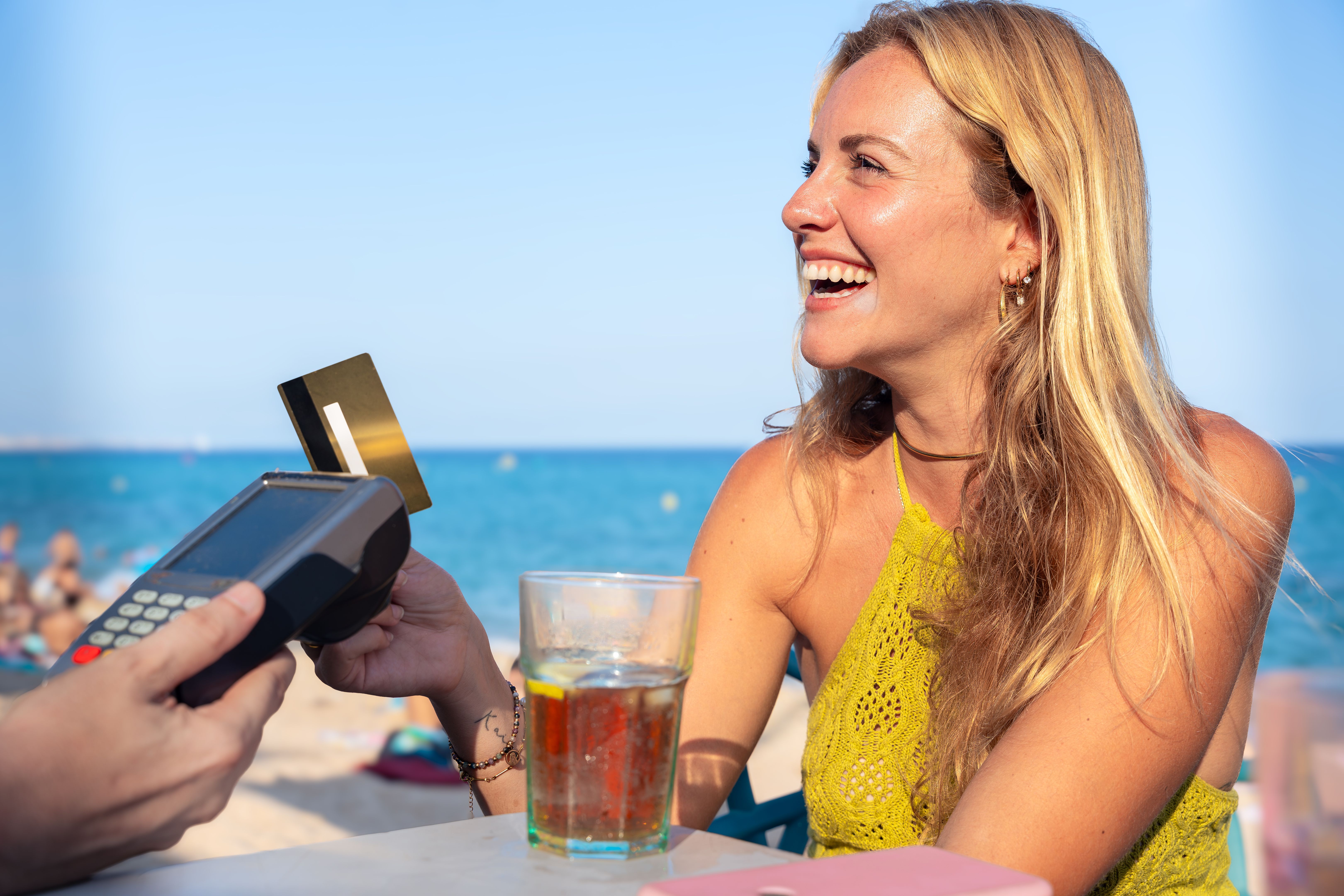 Smiling woman customer paying with contactless credit card in a restaurant.