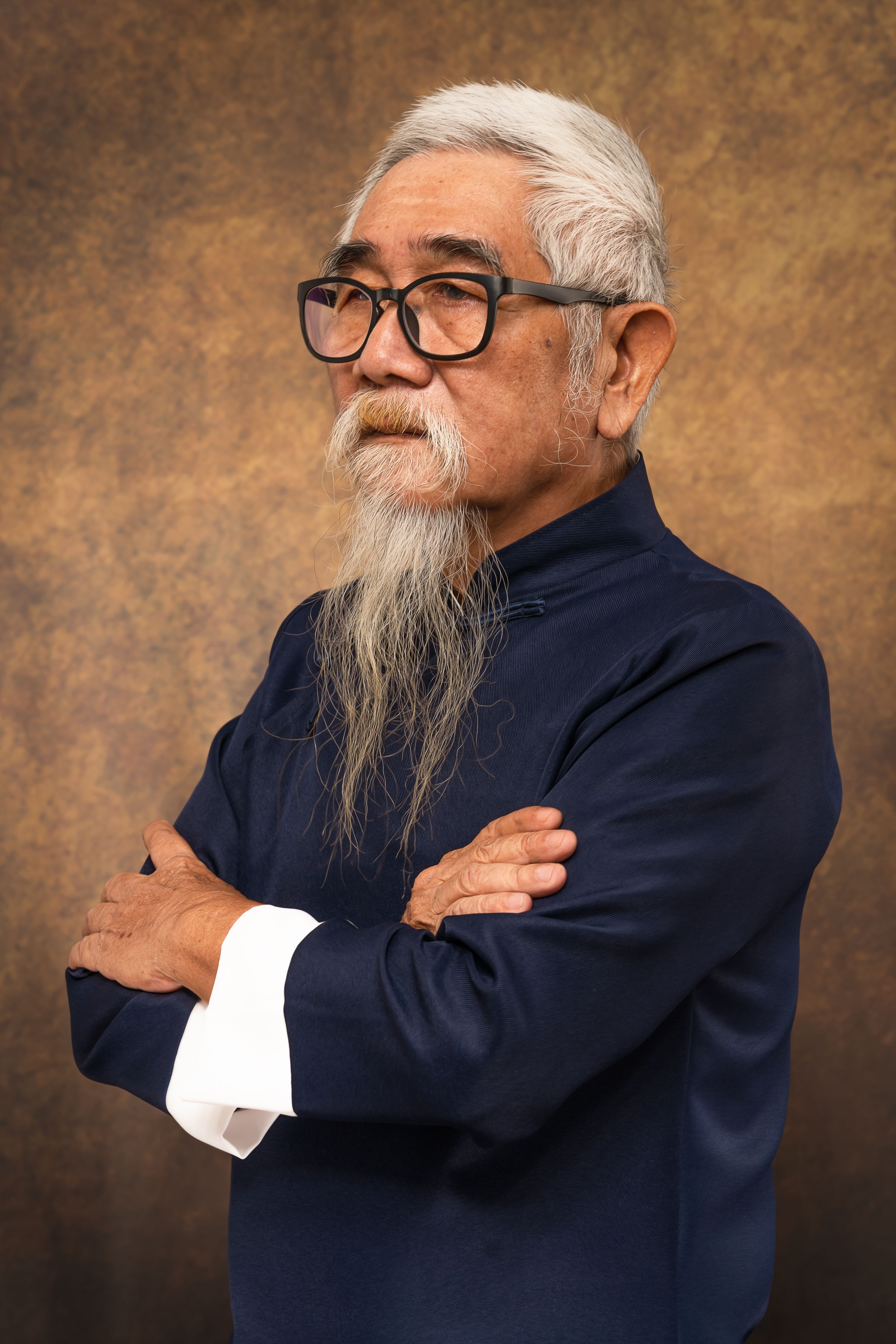 studio portrait of chinese old man wearing eyeglasses with white hair and beard in tradional chinese clothing on studio backdrop background