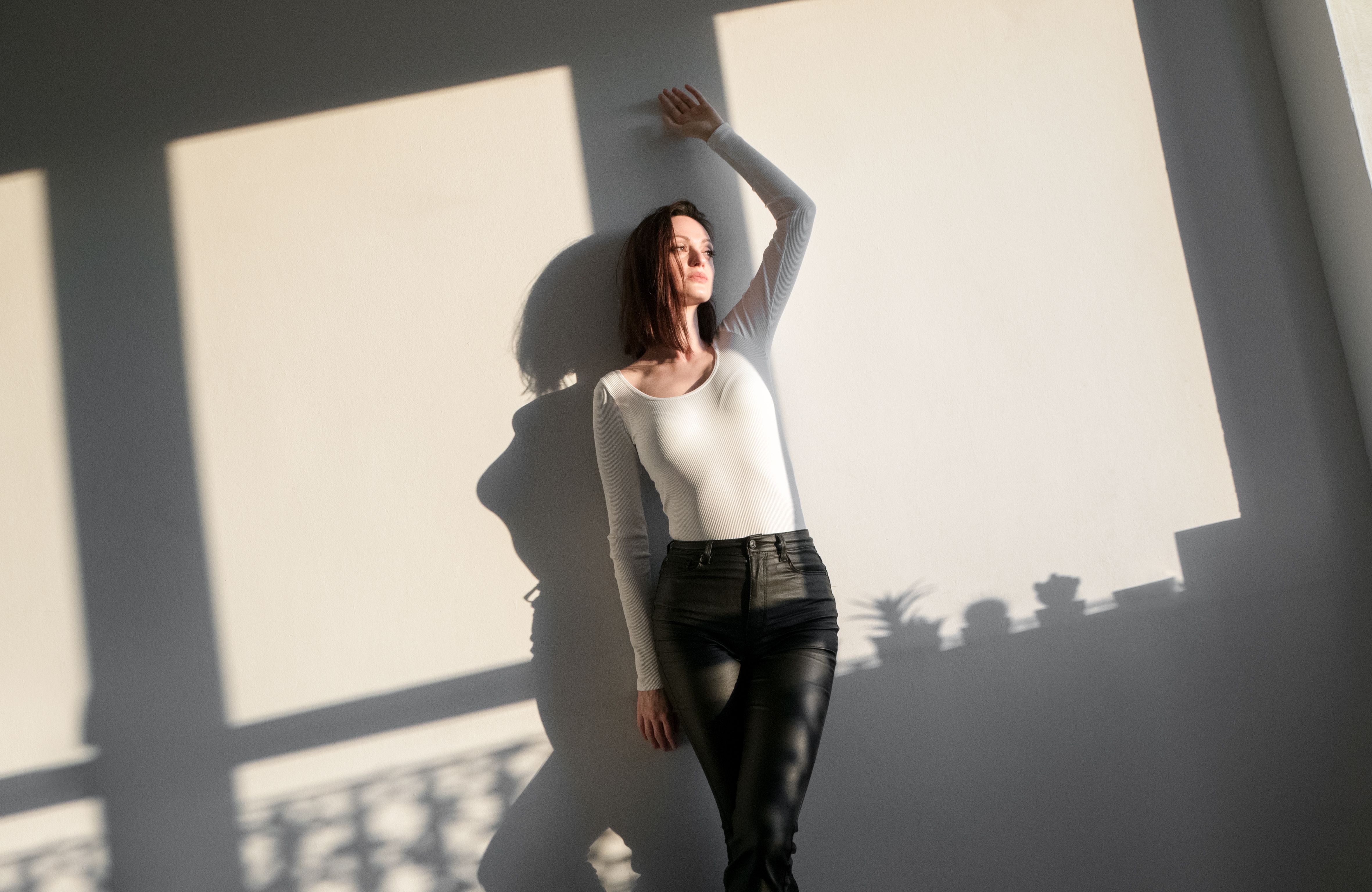 Confident brunette leaning against the wall indoor