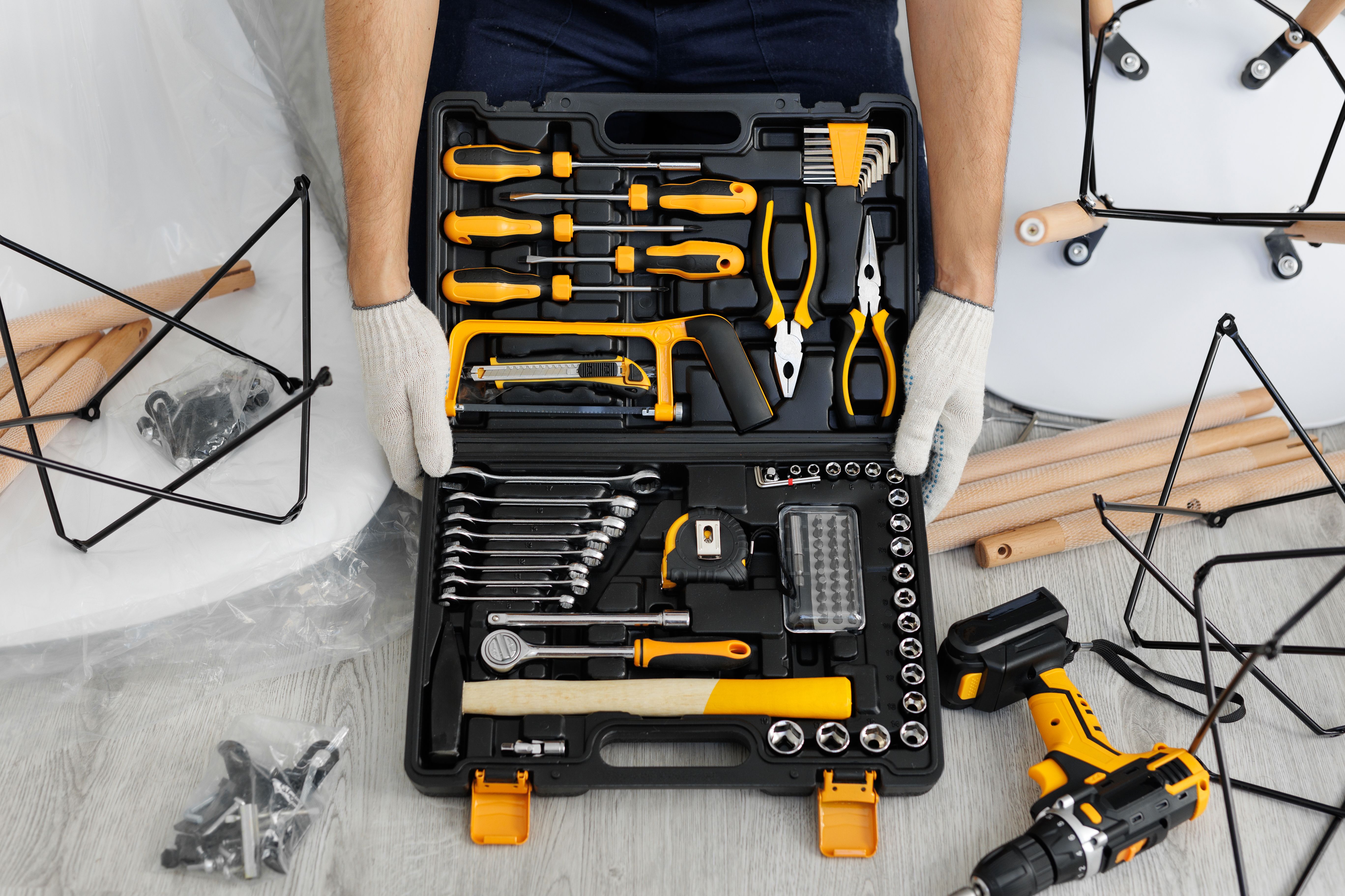 A male craftsman holds a set of tools in a suitcase on the floor in close-up.