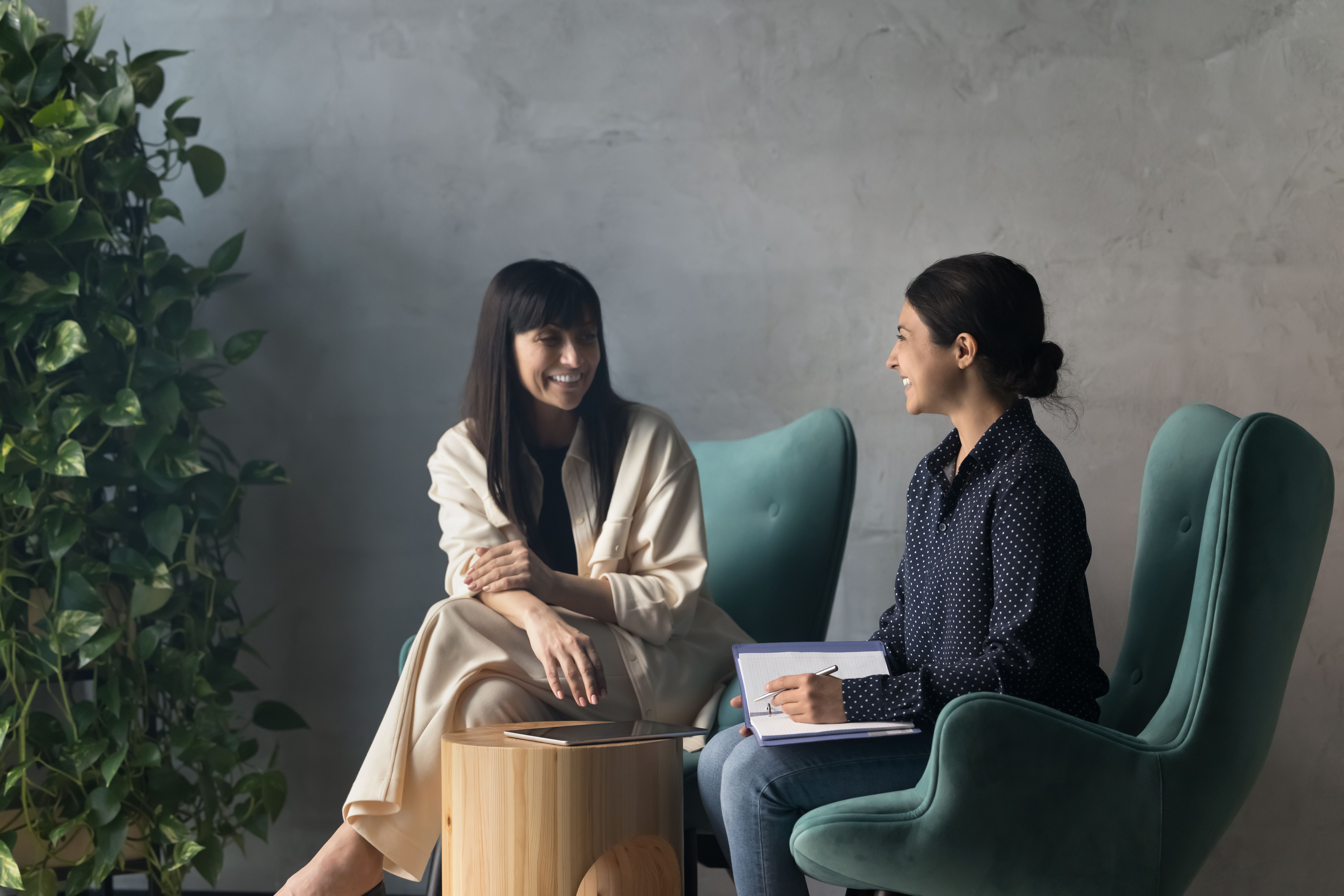 Two businesswomen laughing during meeting in modern cozy office lobby