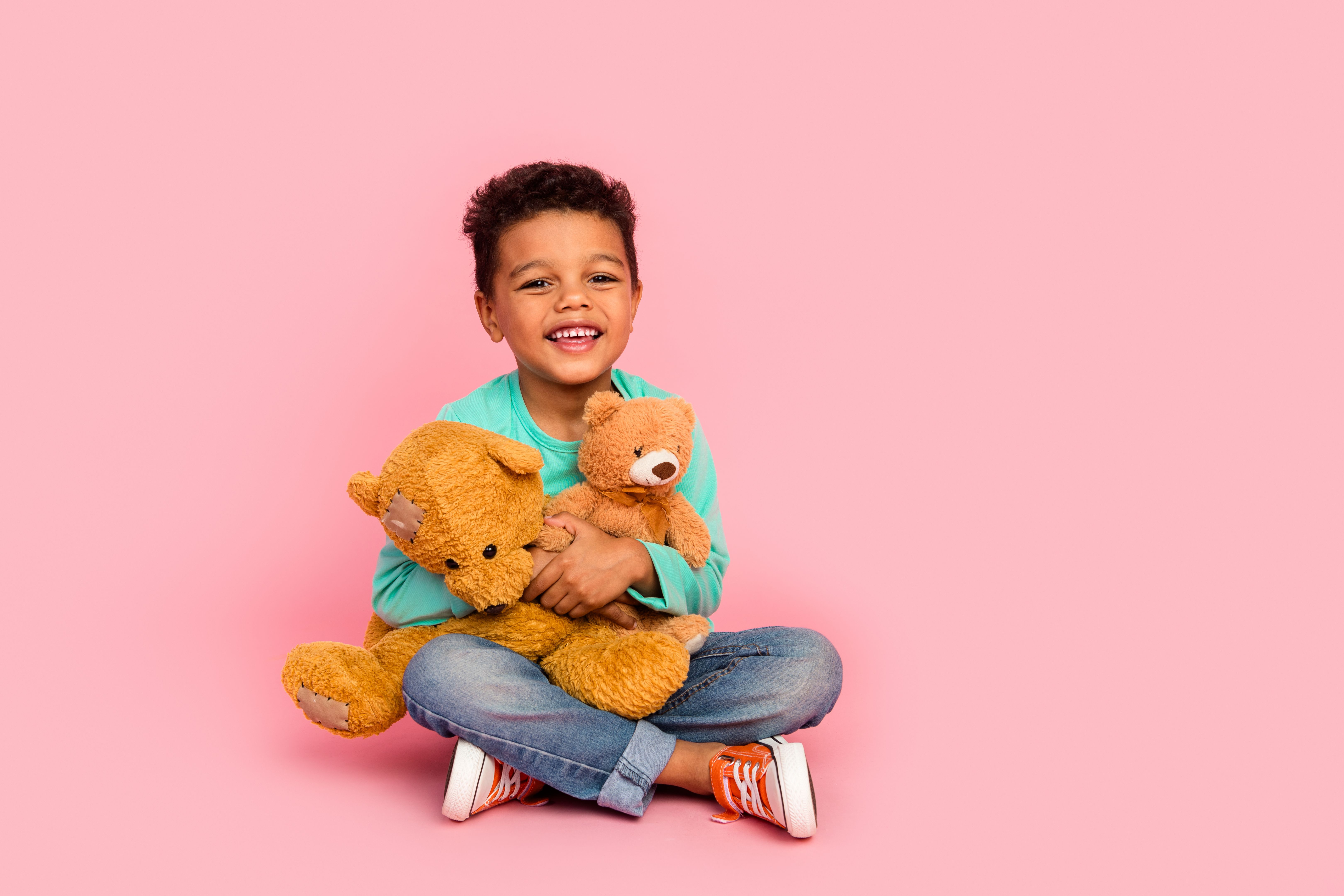 Full length photo of adorable little boy sit floor hold two teddy bears dressed stylish cyan garment isolated on pink color background