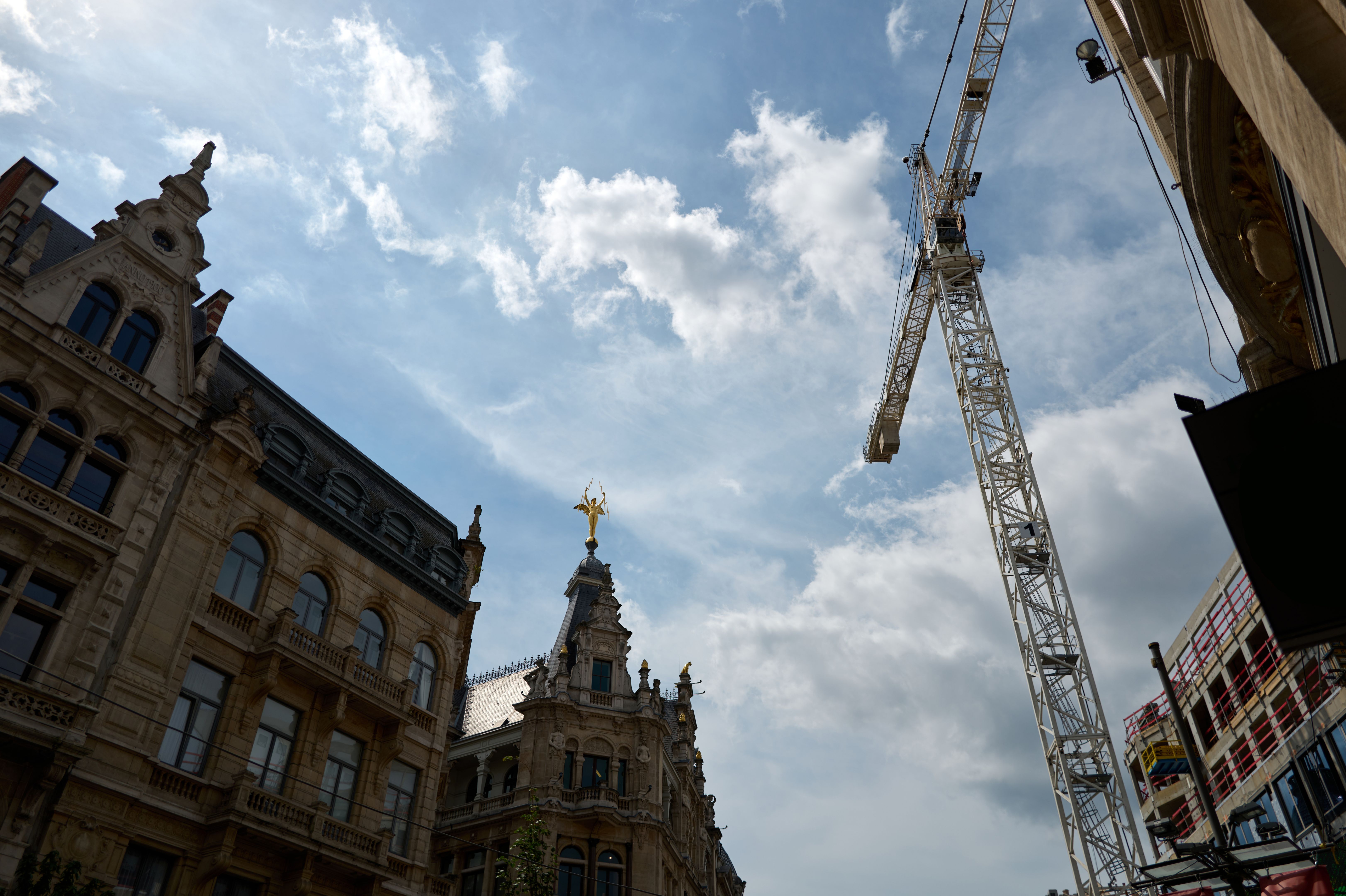 Construction crane towering over historic buildings in antwerp, belgium
