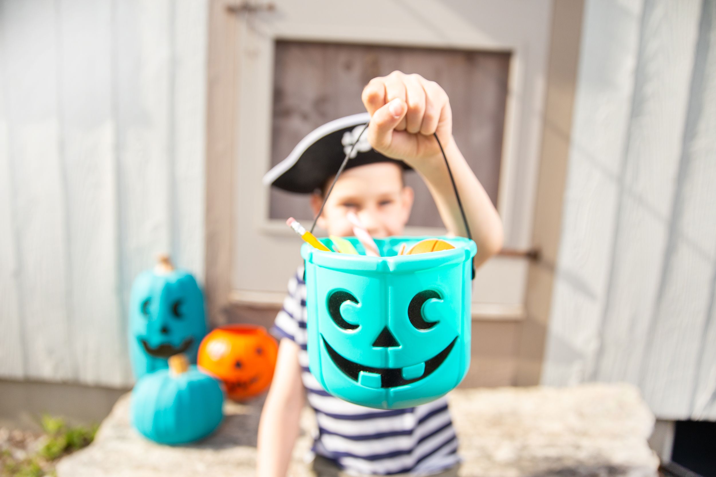 boy in a pirate costume holds a bucket with inedible gifts