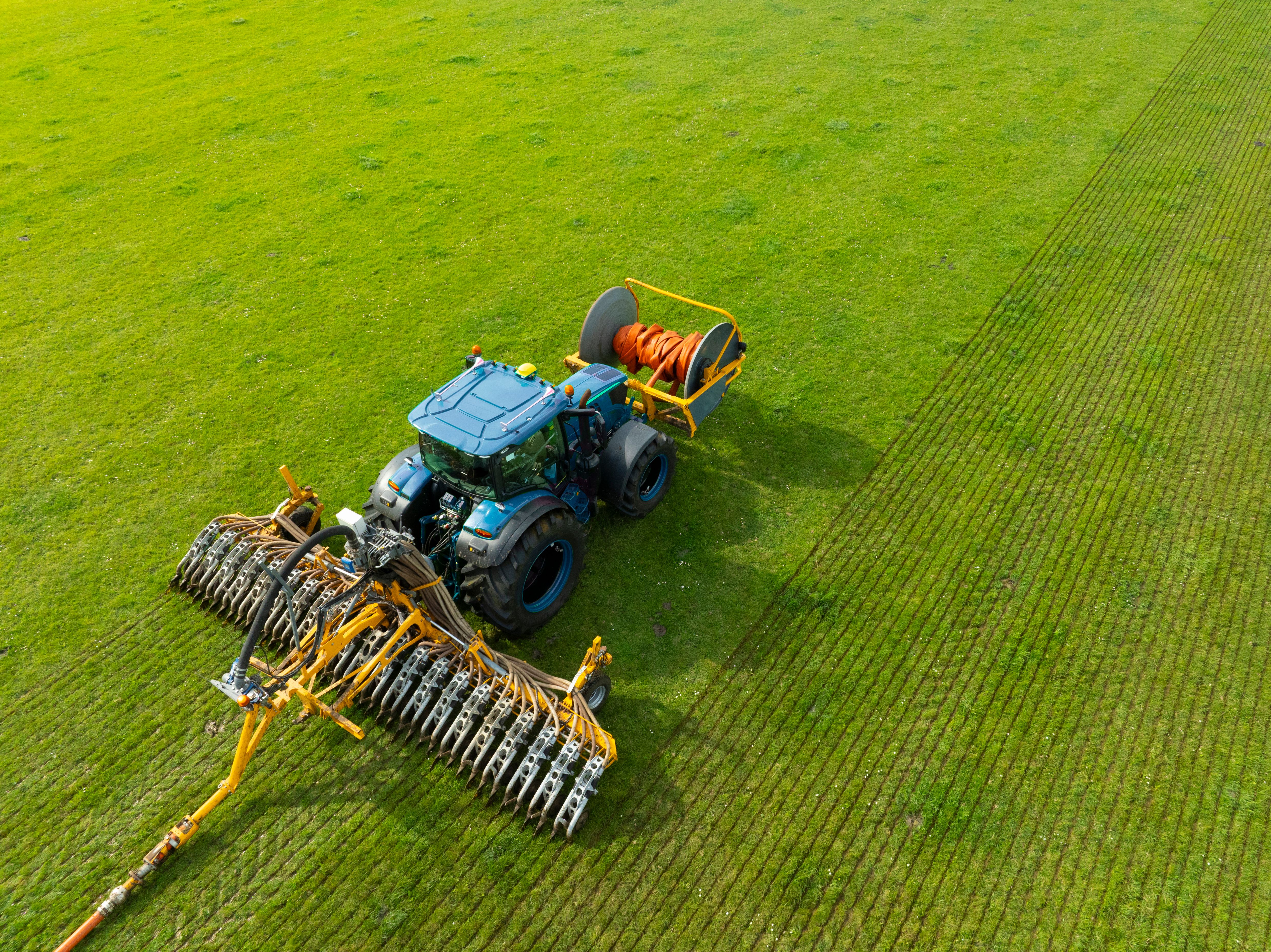Tractor injecting livestock liquid manure in a field seen from above