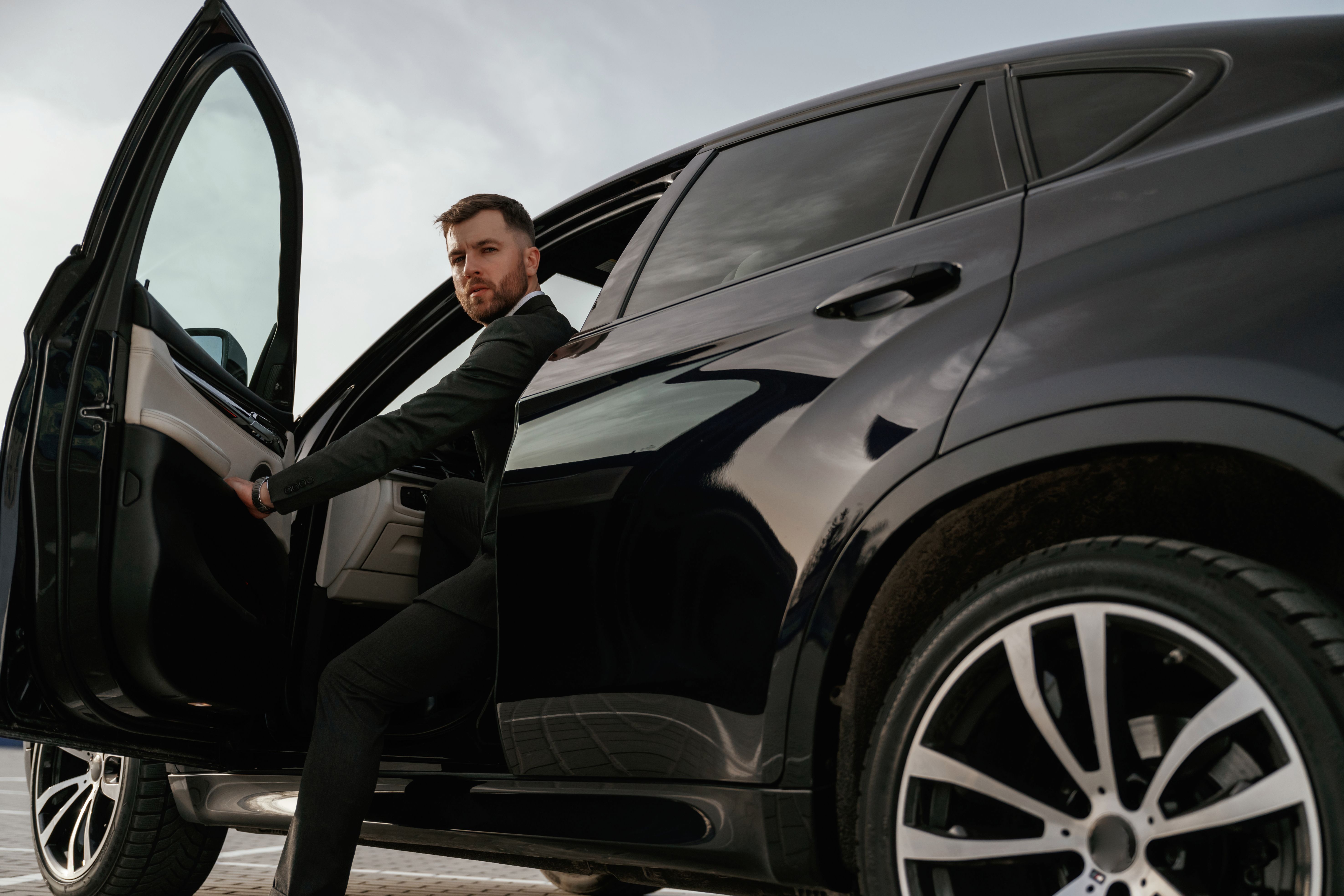 Man in black suit is sitting in the car, opening the door