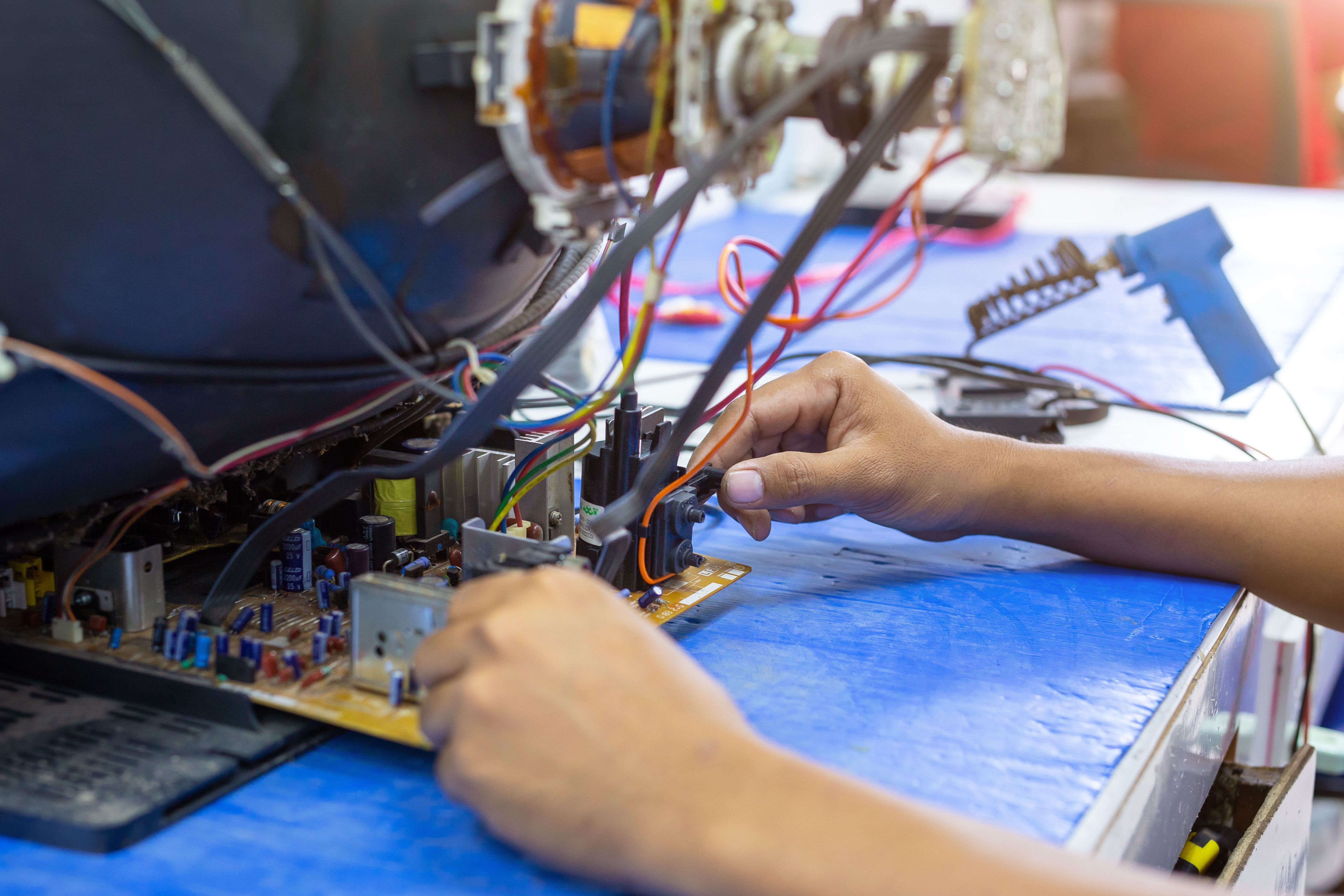 A young technician repairing a television  on work table.