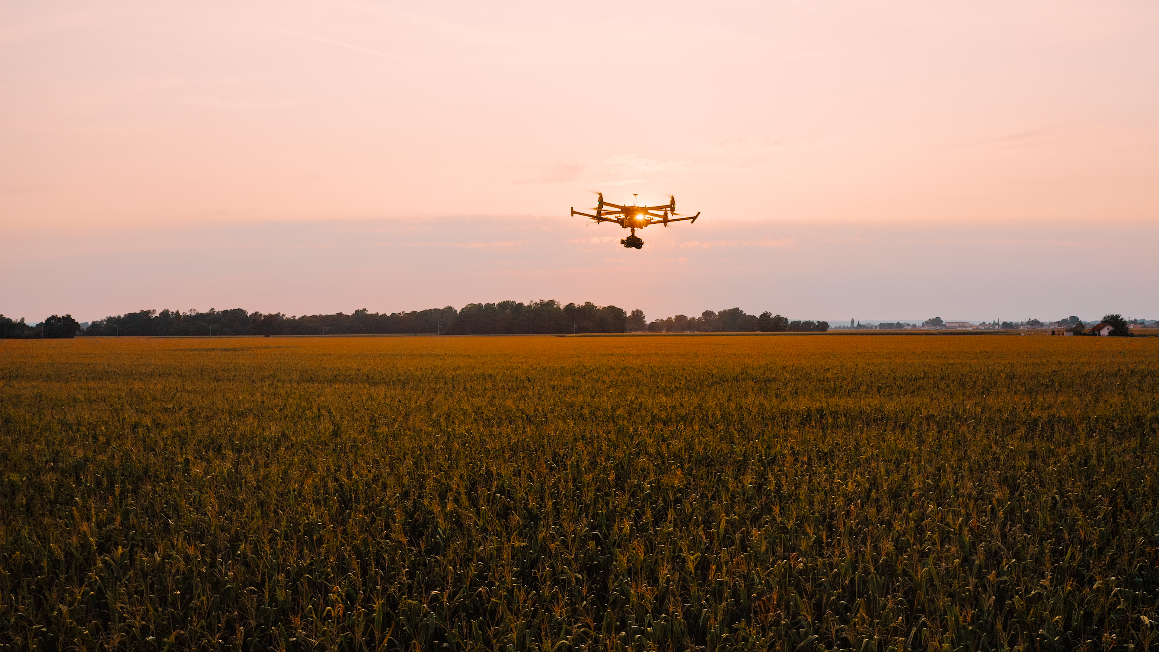 Drone flying above field at sunset