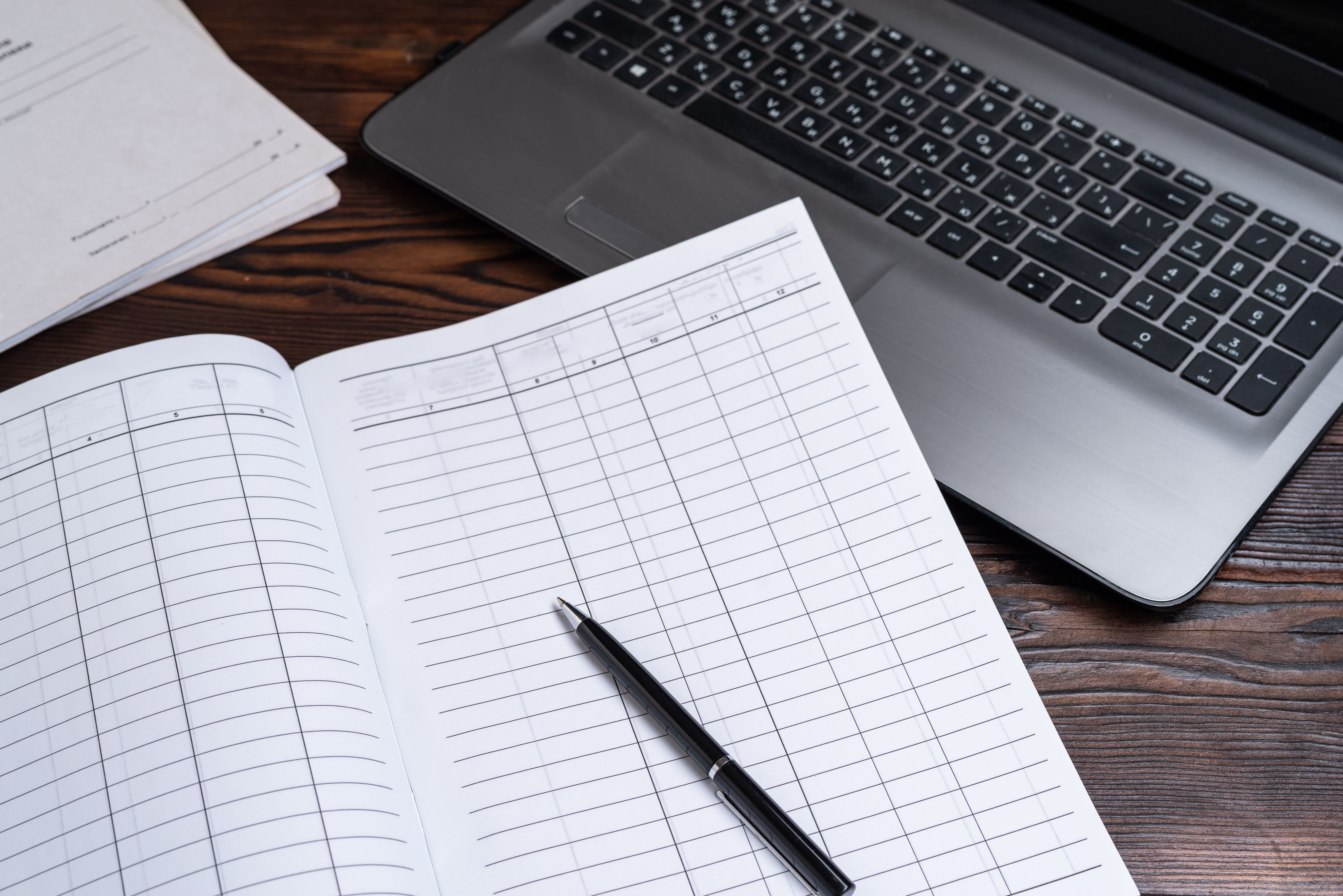 Accounting journal and laptop. Hand on book for accounting. Keep bookkeeping. Accounting journal and laptop. Hand on book for accounting. Keep bookkeeping.