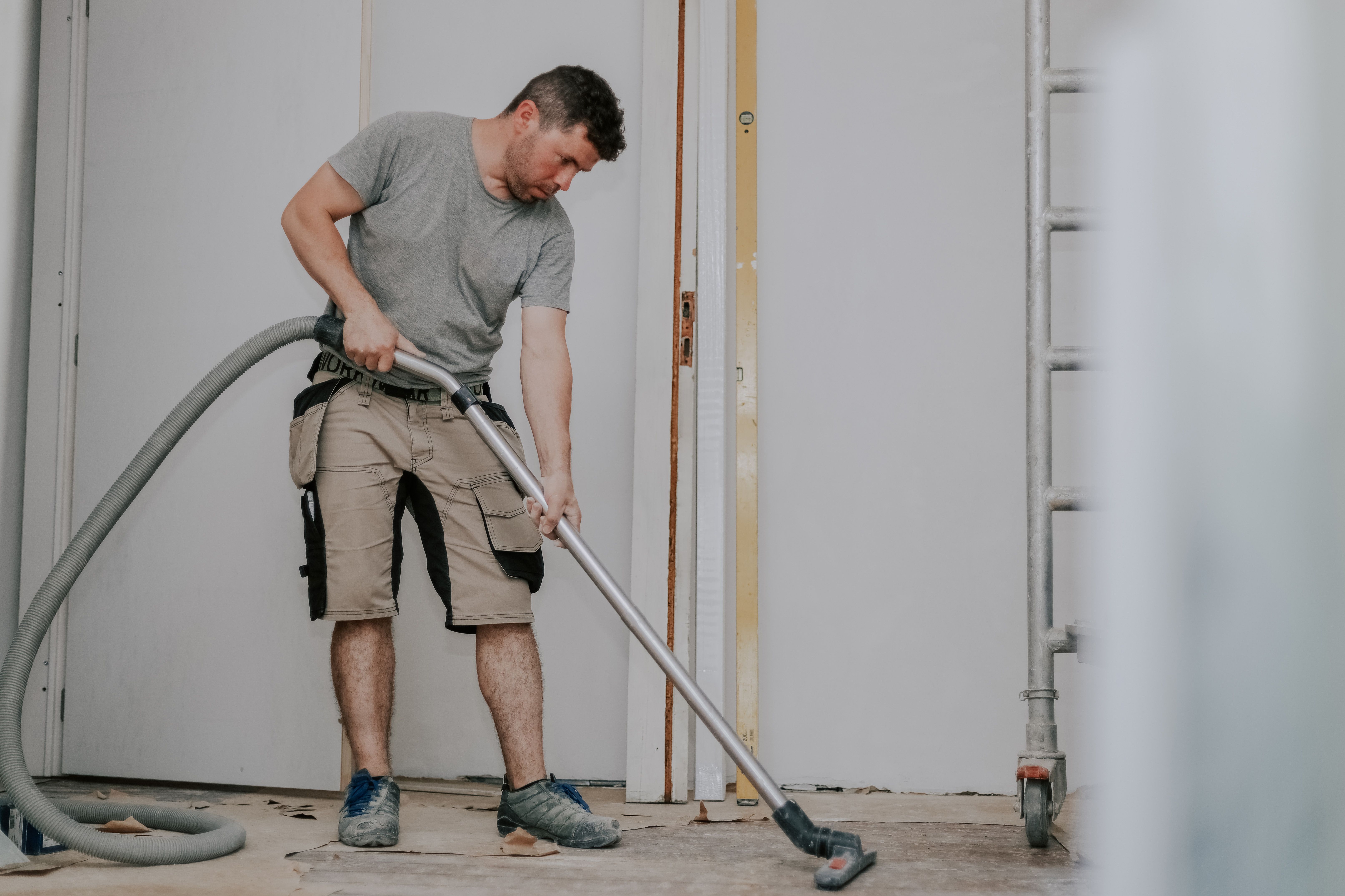 A Young Man Vacuums The Floor With A Construction Vacuum Cleaner.