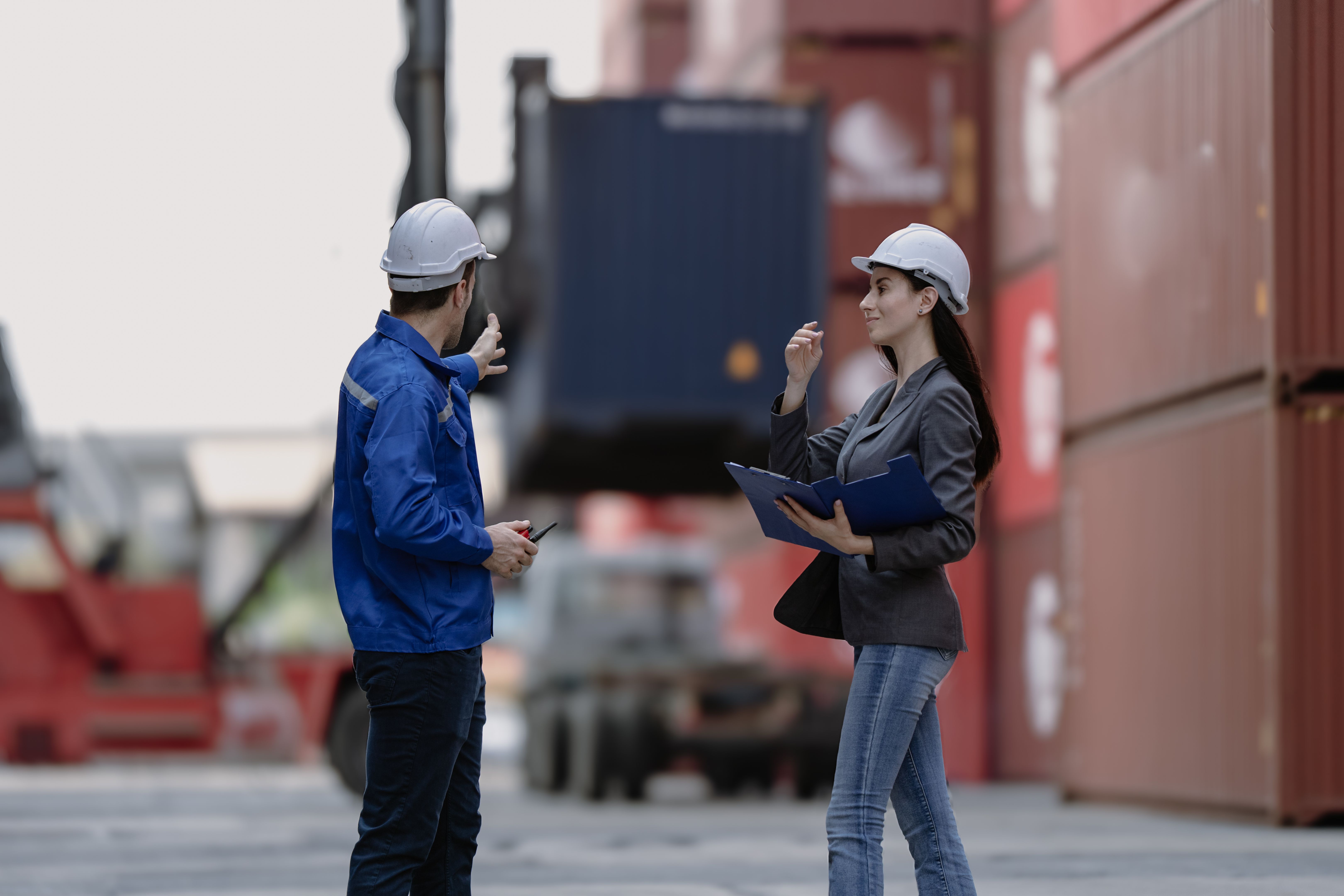 Industrial engineer woman working at import export distribution port. Diverse people work together