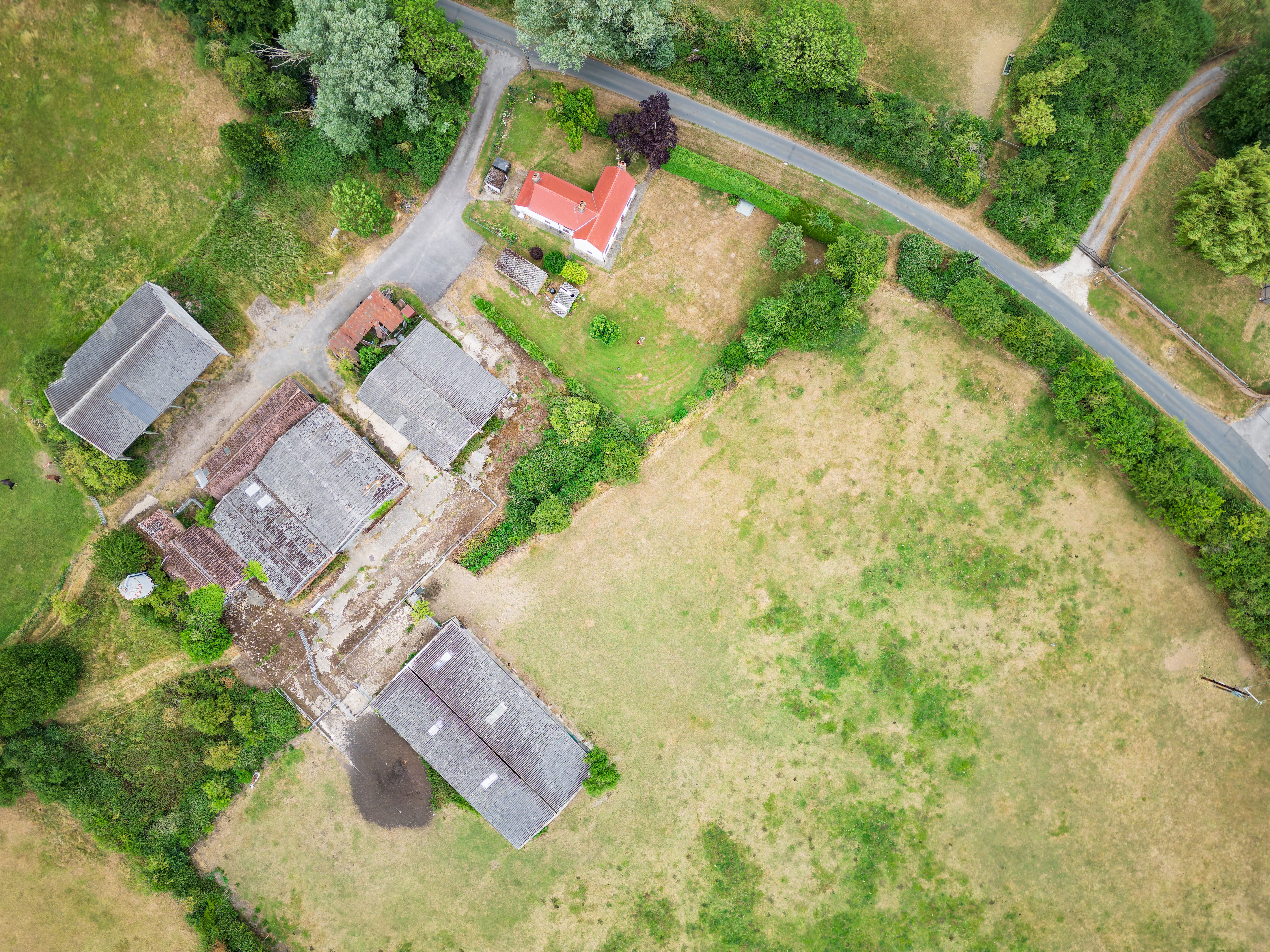 Drone view of an old farm house seen in lush pasture.