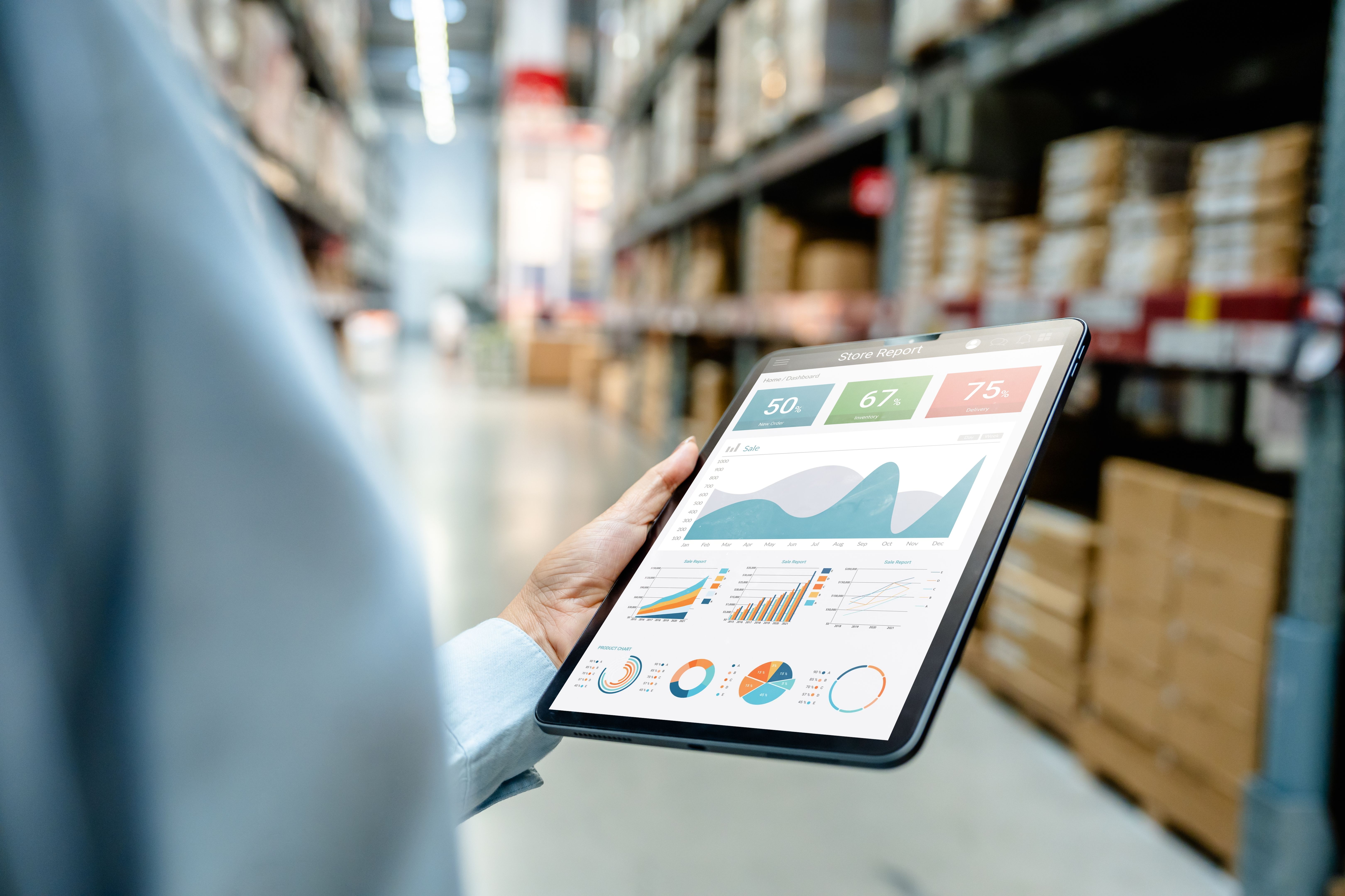 Warehouse employee using digital tablet to monitor business analytics dashboard in modern storage facility for real-time inventory tracking, logistics management, and operational performance.
