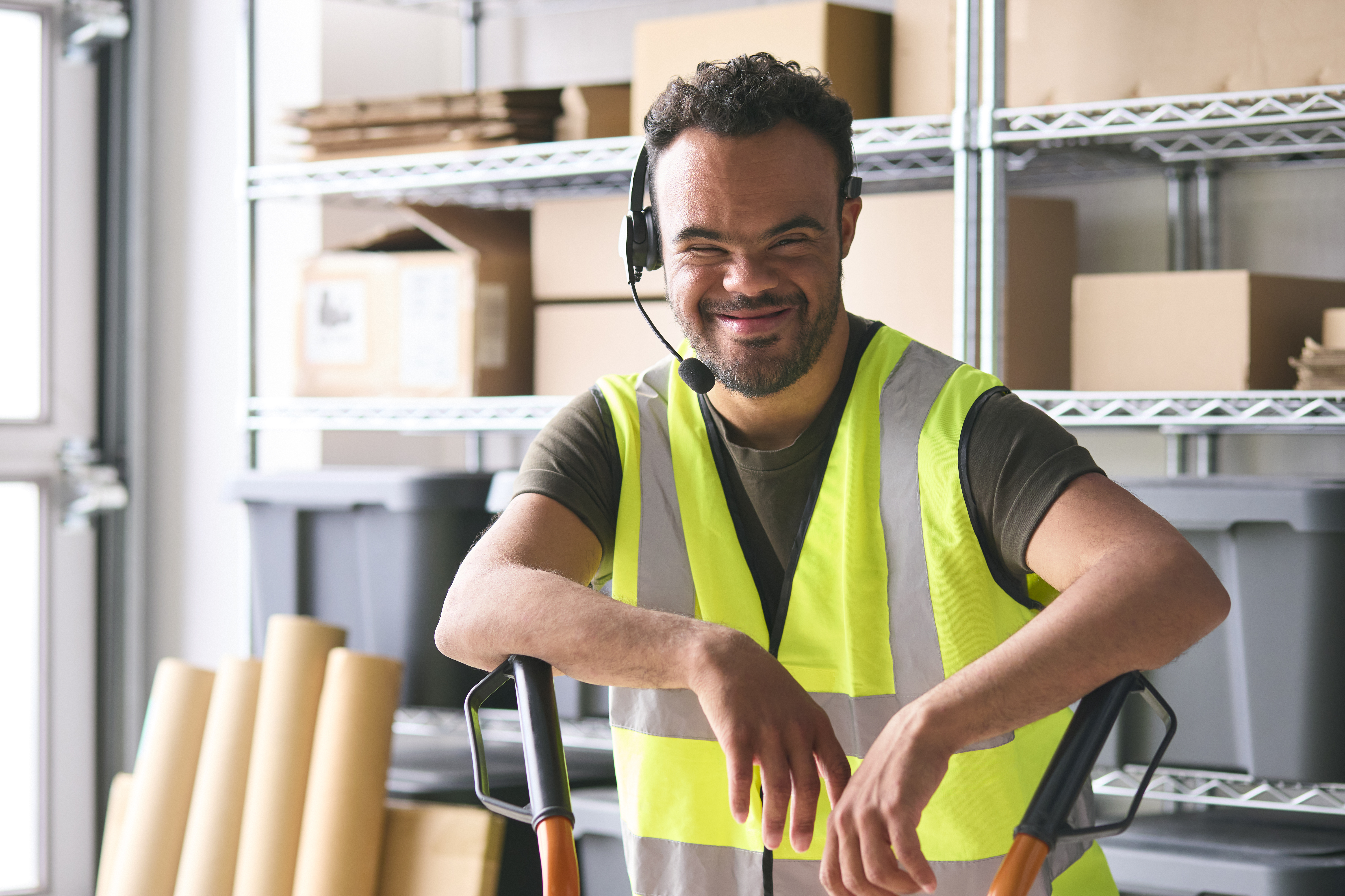 Portrait Of Man With Down Syndrome Working In Warehouse Wearing Headset