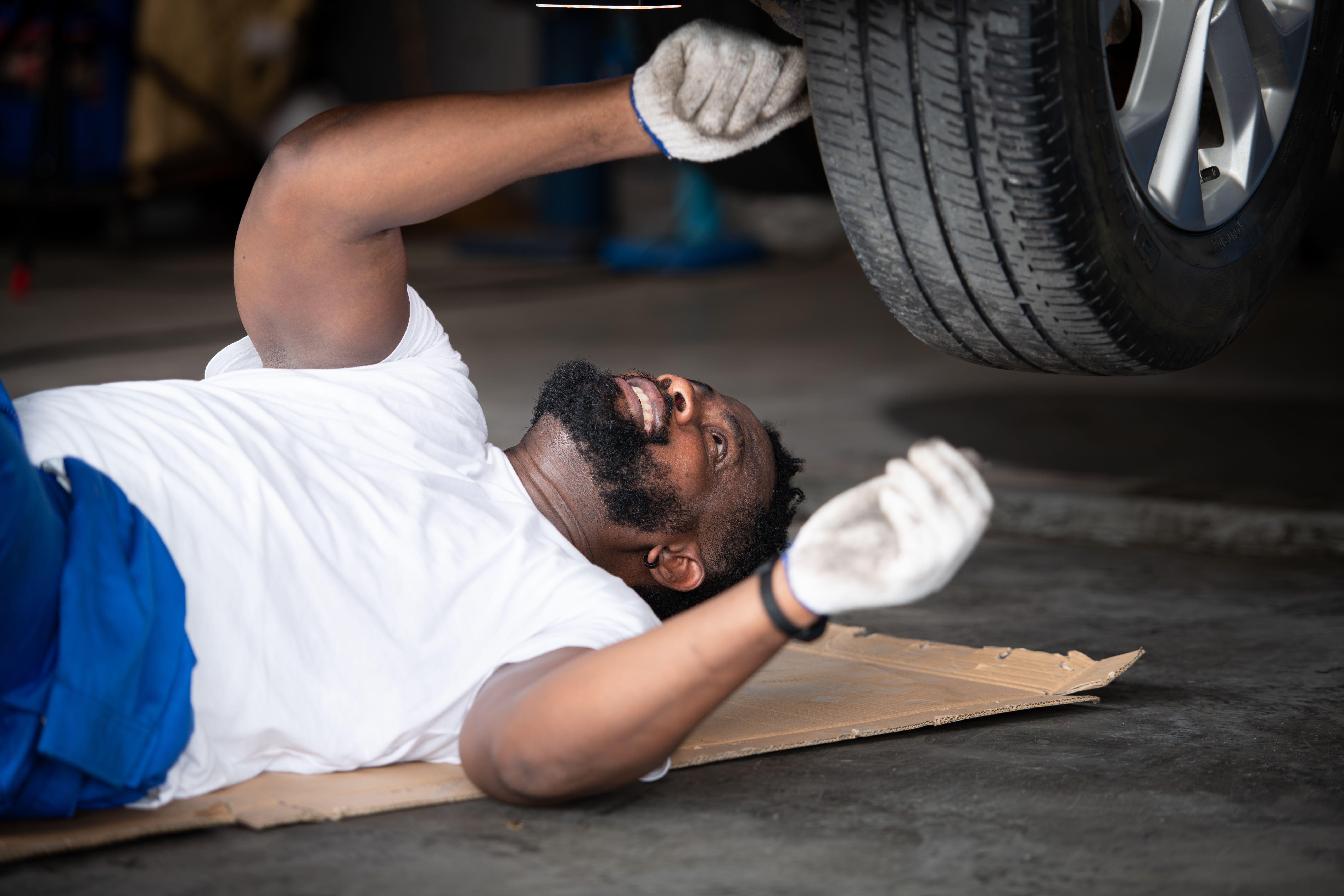 Car mechanic working in an auto repair shop, Check the operation of the engine of under the car that comes in for repairs at the auto repair shop.