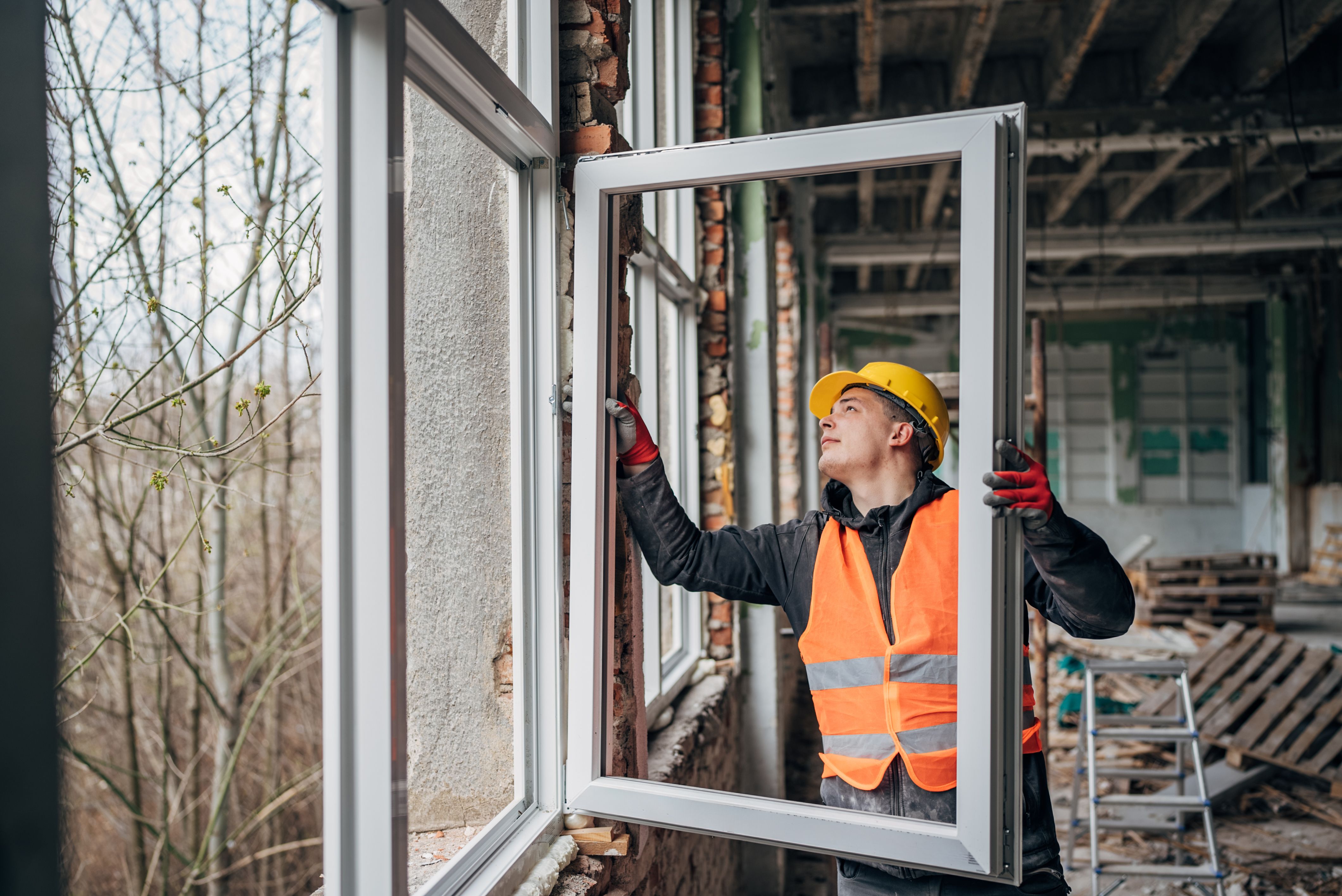 Craftsmen installing window frame at construction site Craftsmen installing window frame at construction site