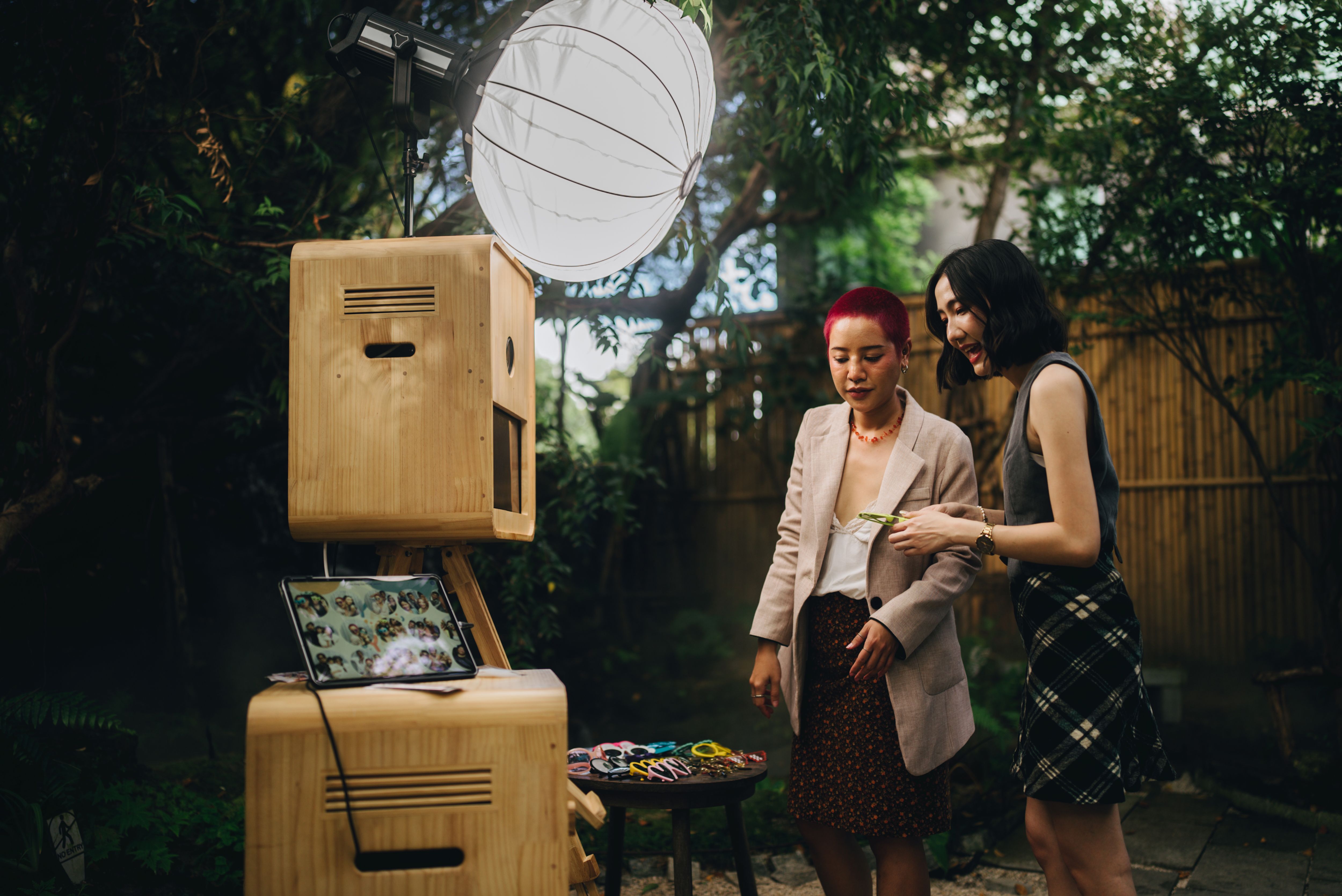 Female friends having fun at a wedding in front of a photo booth Take a photo and choose to save it on a mobile phone. Female friends having fun at a wedding in front of a photo booth Take a photo and choose to save it on a mobile phone.