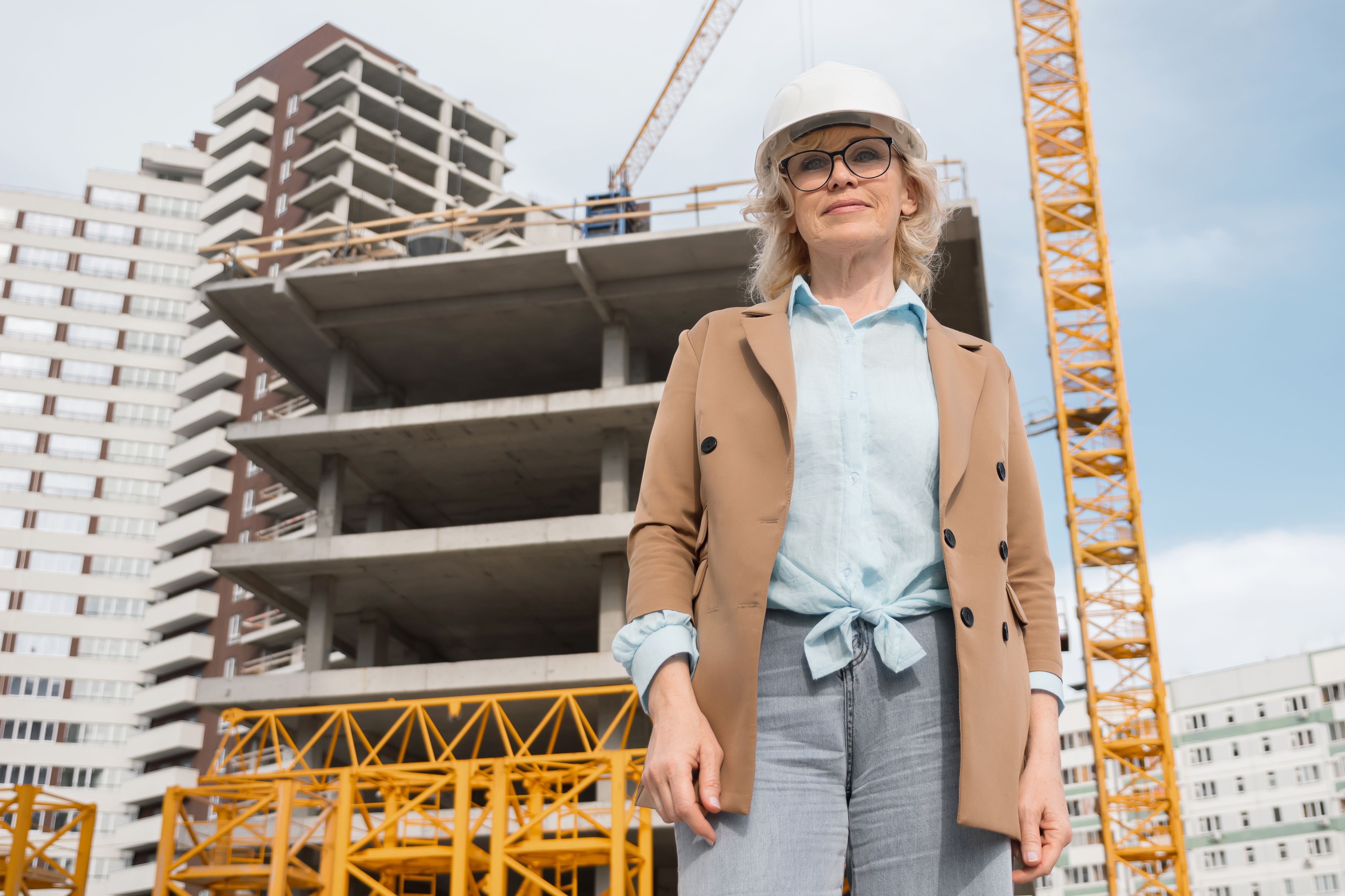 Blonde businesswoman standing against building construction Blonde businesswoman standing against building construction