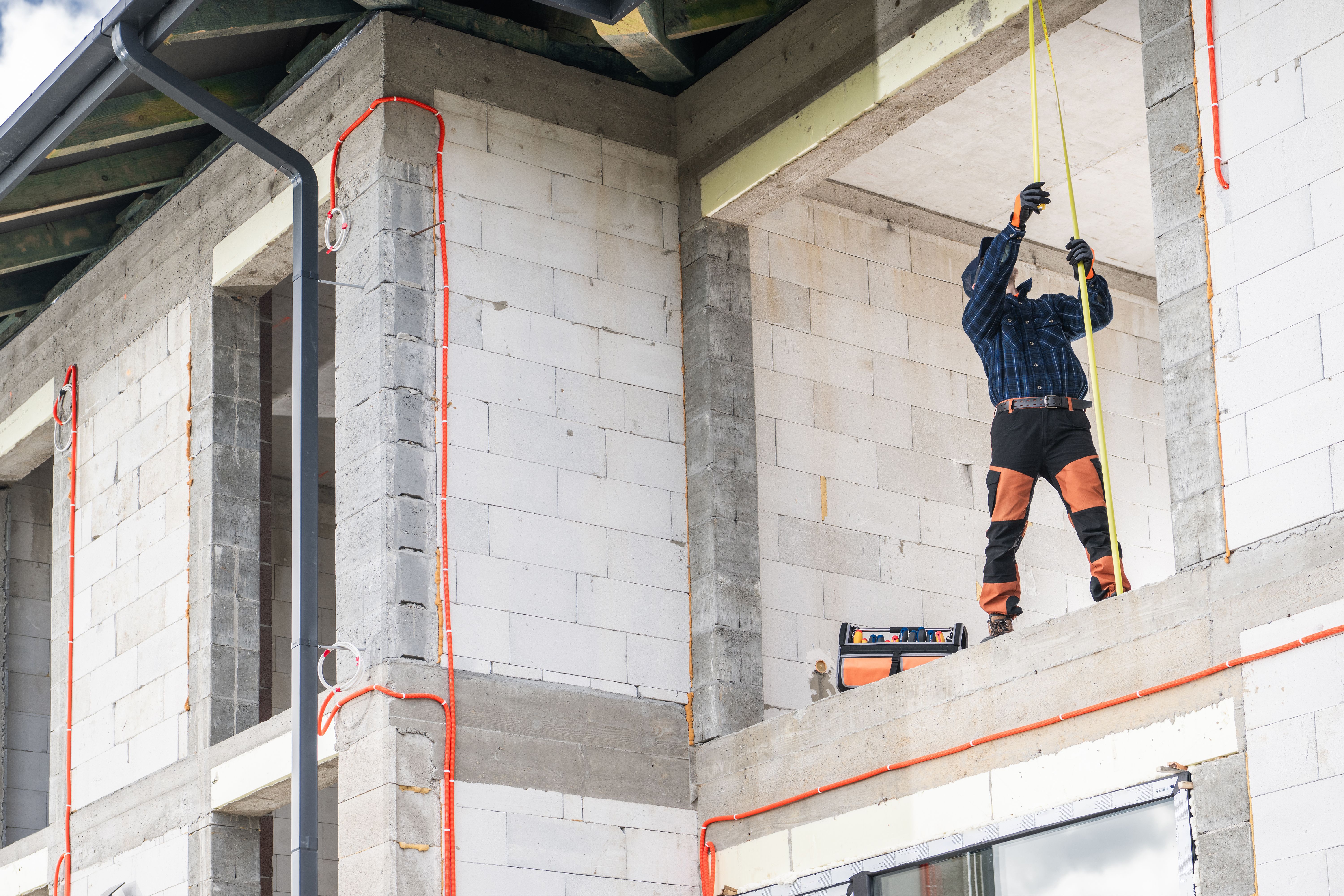 Worker Measuring Height at Construction Site With Safety Gear