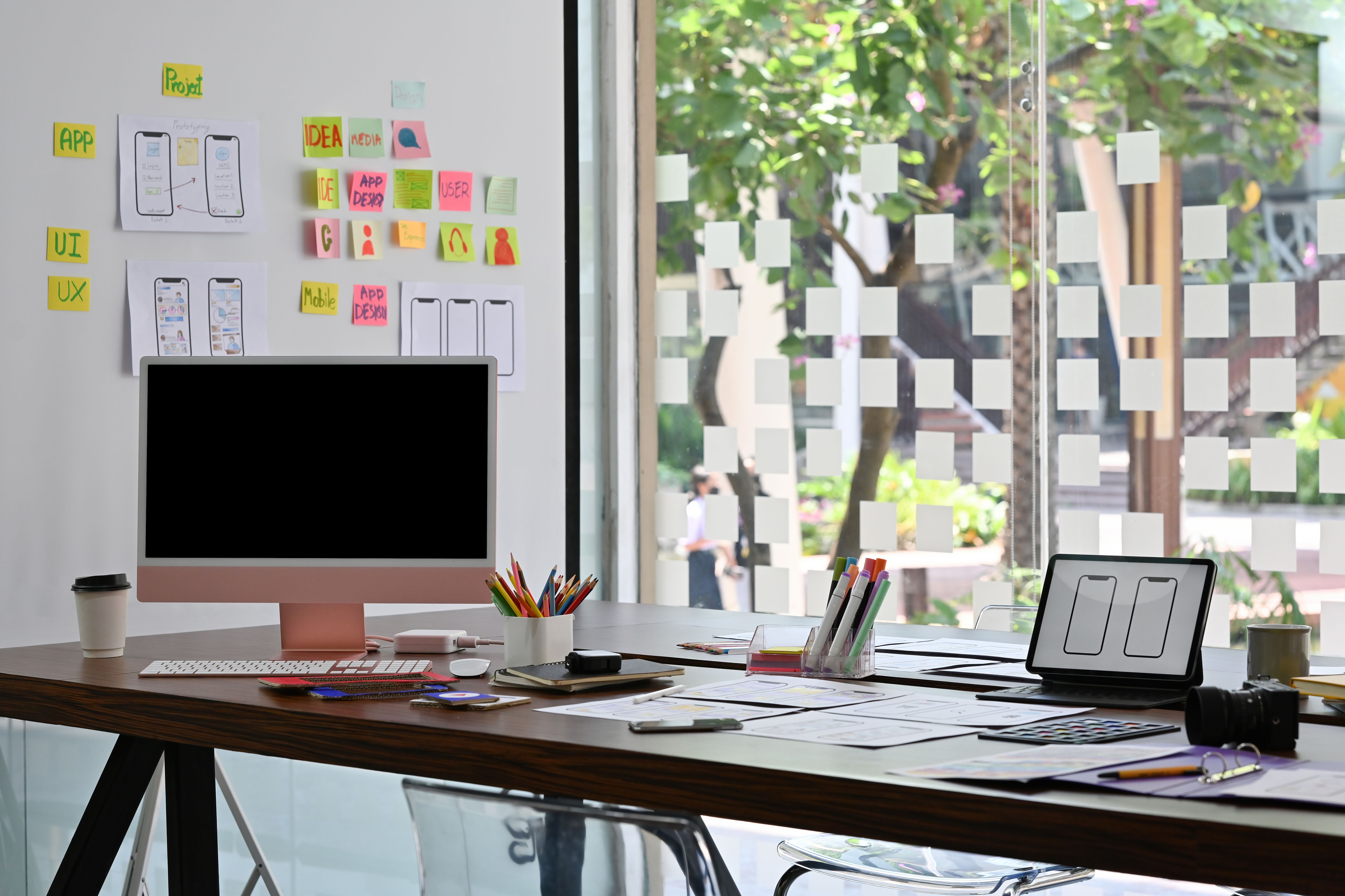 Overview of the busy modern office decoration with black computer monitor screen next to any gadgets over blurred information on a whiteboard as background. Business and Technology concepts.