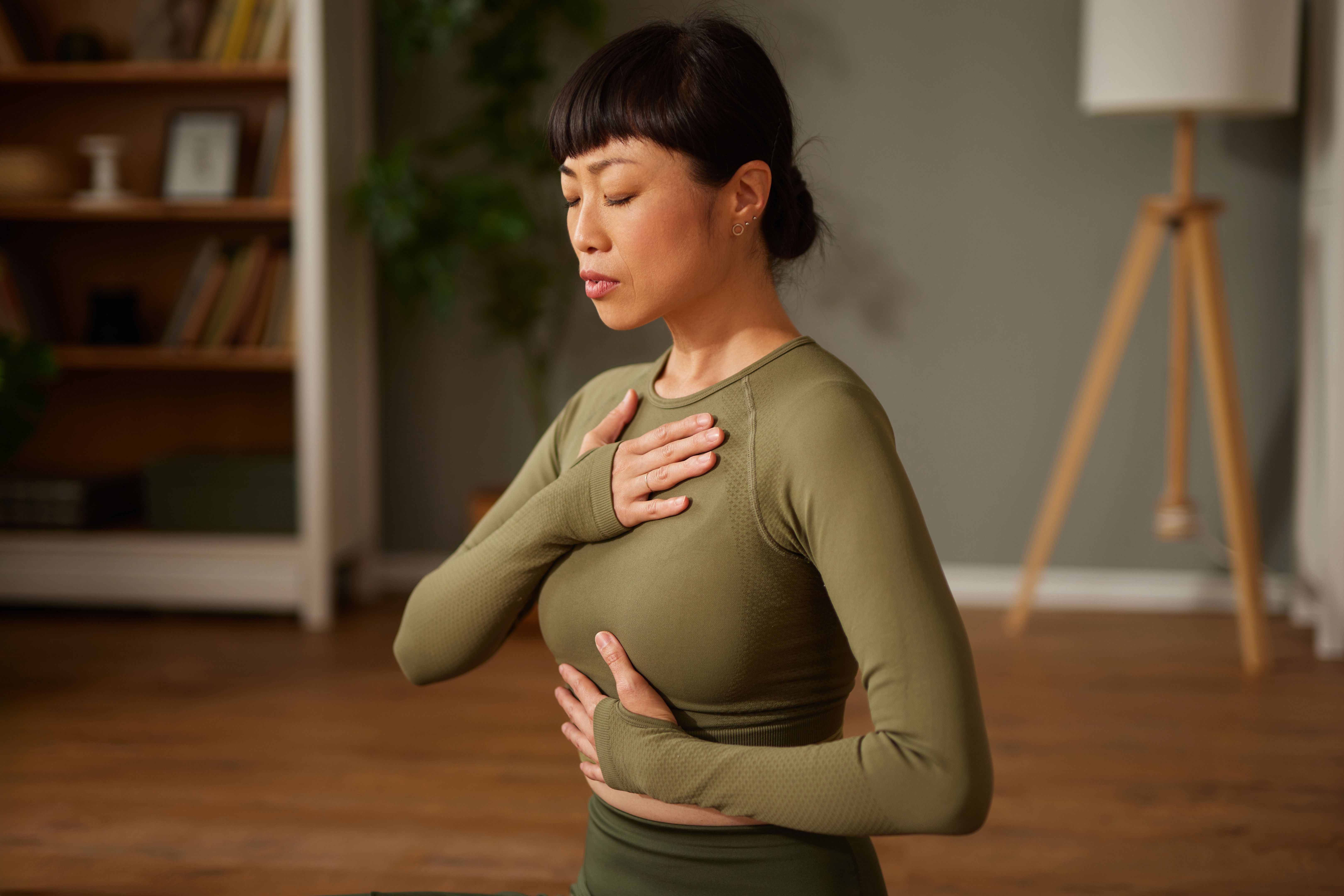 Beautiful Asian woman doing yoga or meditating at home