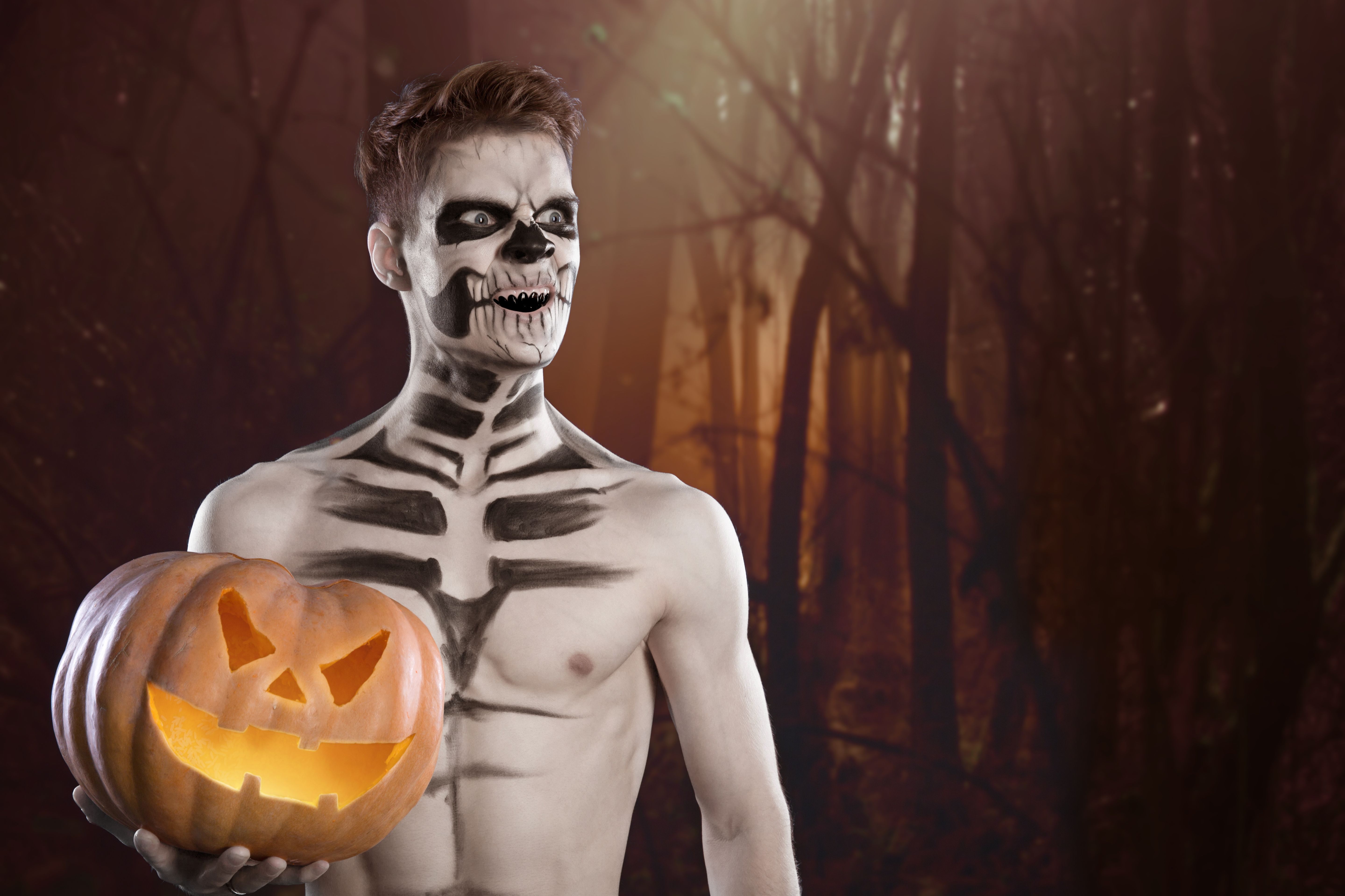 Man in scary Halloween make up holding pumpkin Man in scary Halloween make up holding pumpkin