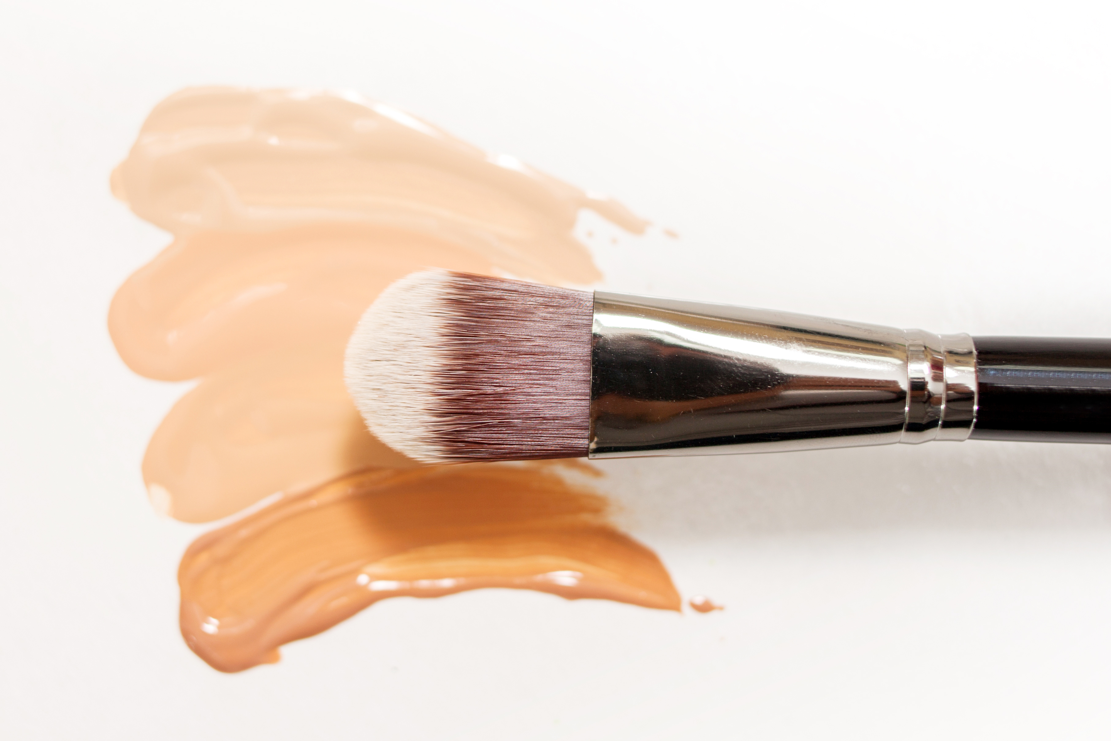 Foundation cream drops and smears of different shades for different skin types with brushes for application and shading.