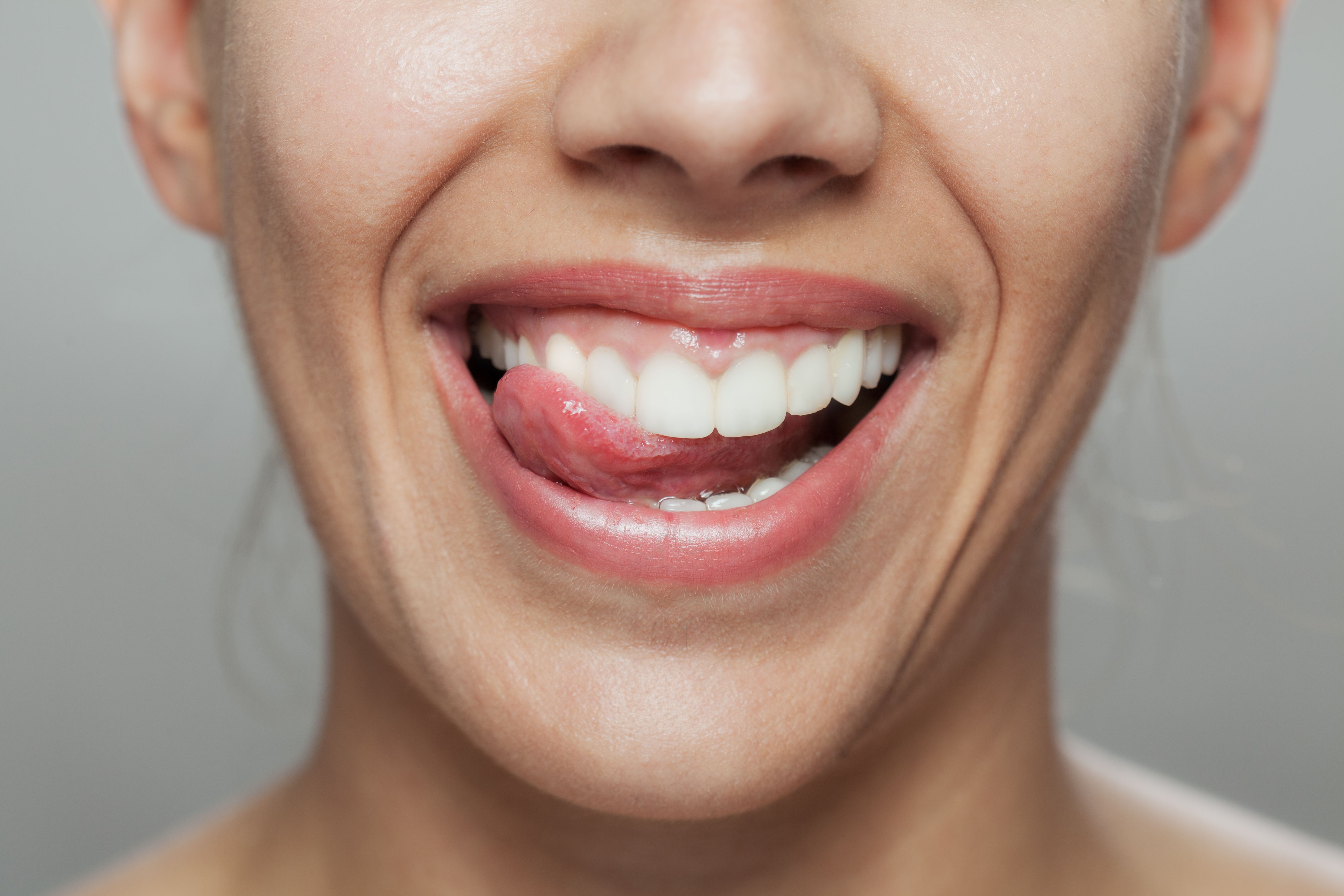 Close-up of a cheerful woman licking her lips, highlighting dental health and joy Close-up of a cheerful woman licking her lips, highlighting dental health and joy