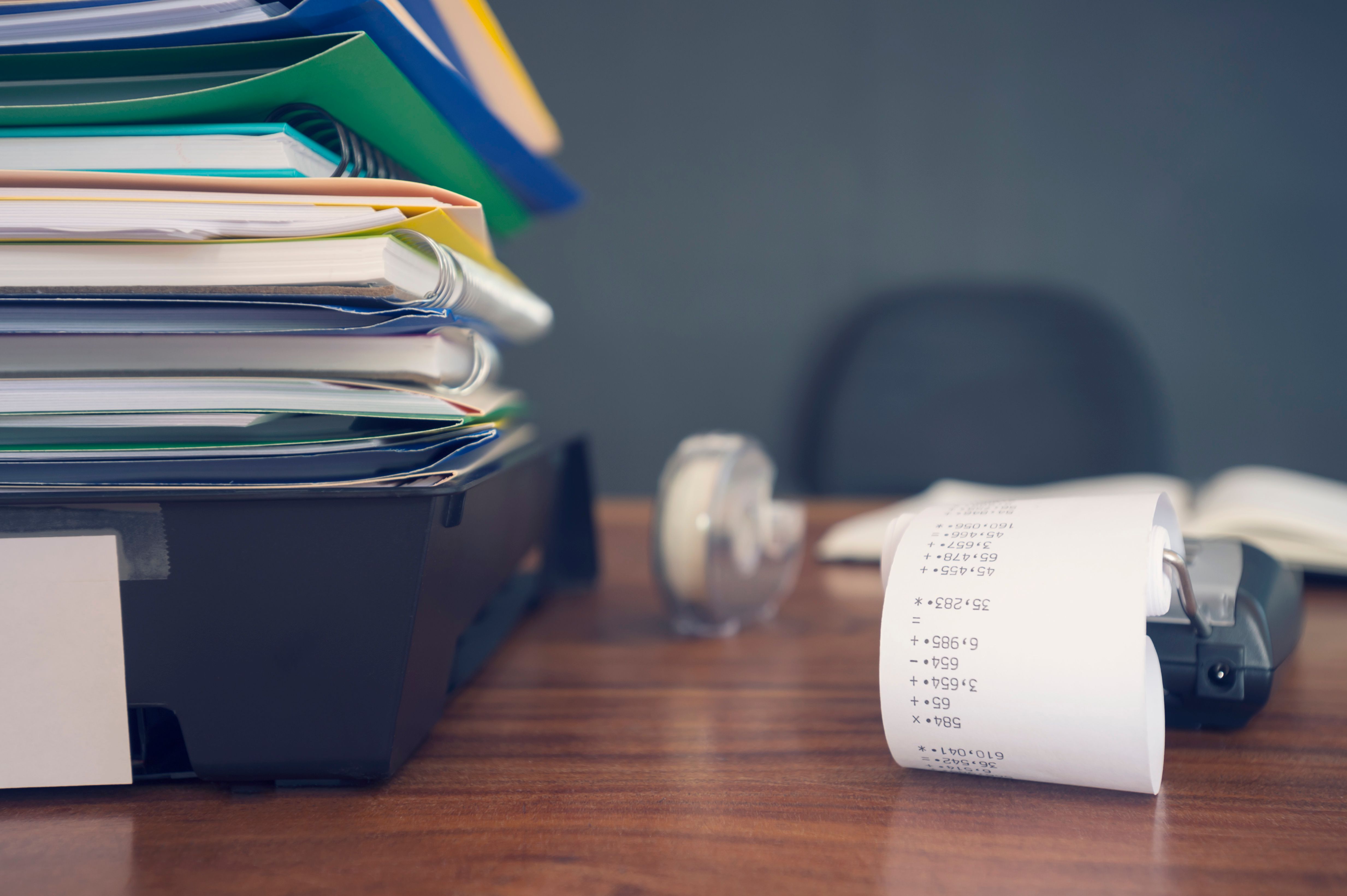 Large stack of paperwork and files with calculator.
