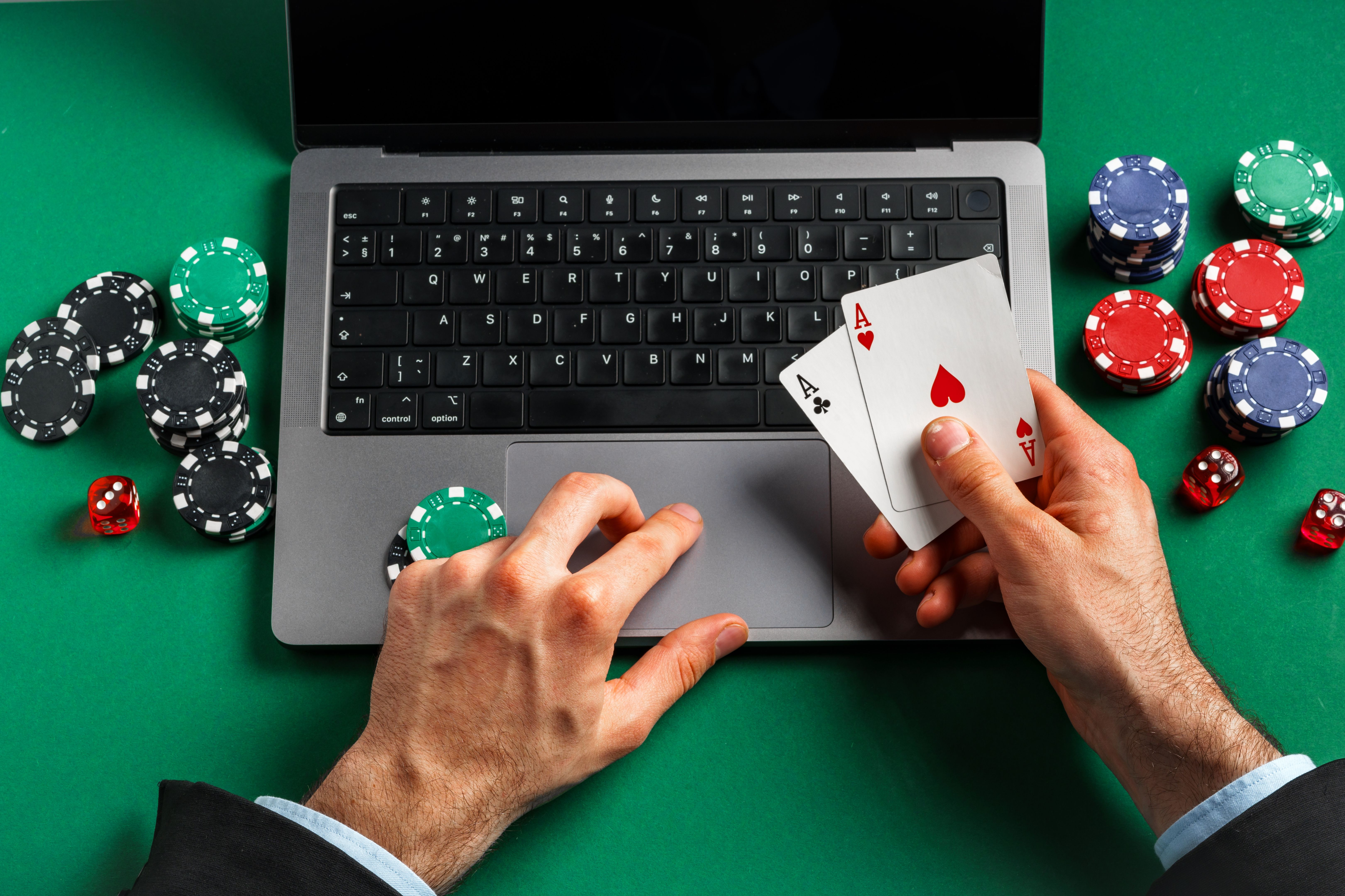 Person Playing Online Poker With Laptop and Cards