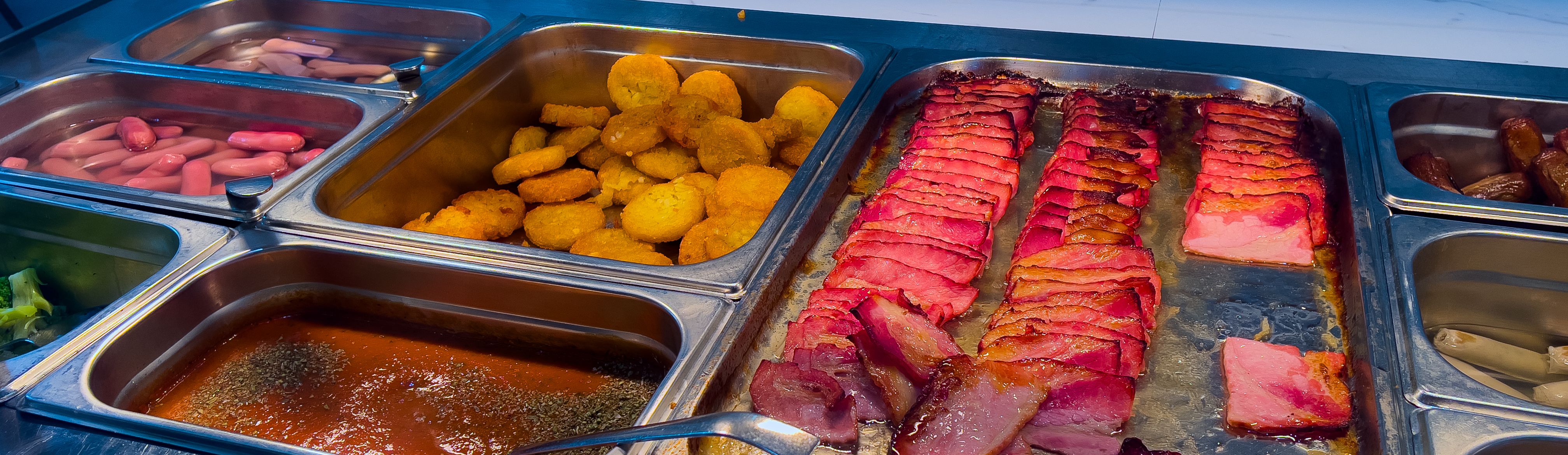 Traditional English breakfast on a hotel buffet: bacon, hash browns, beans, sausages, and sauce. Popular in hotels, schools, and university dining halls