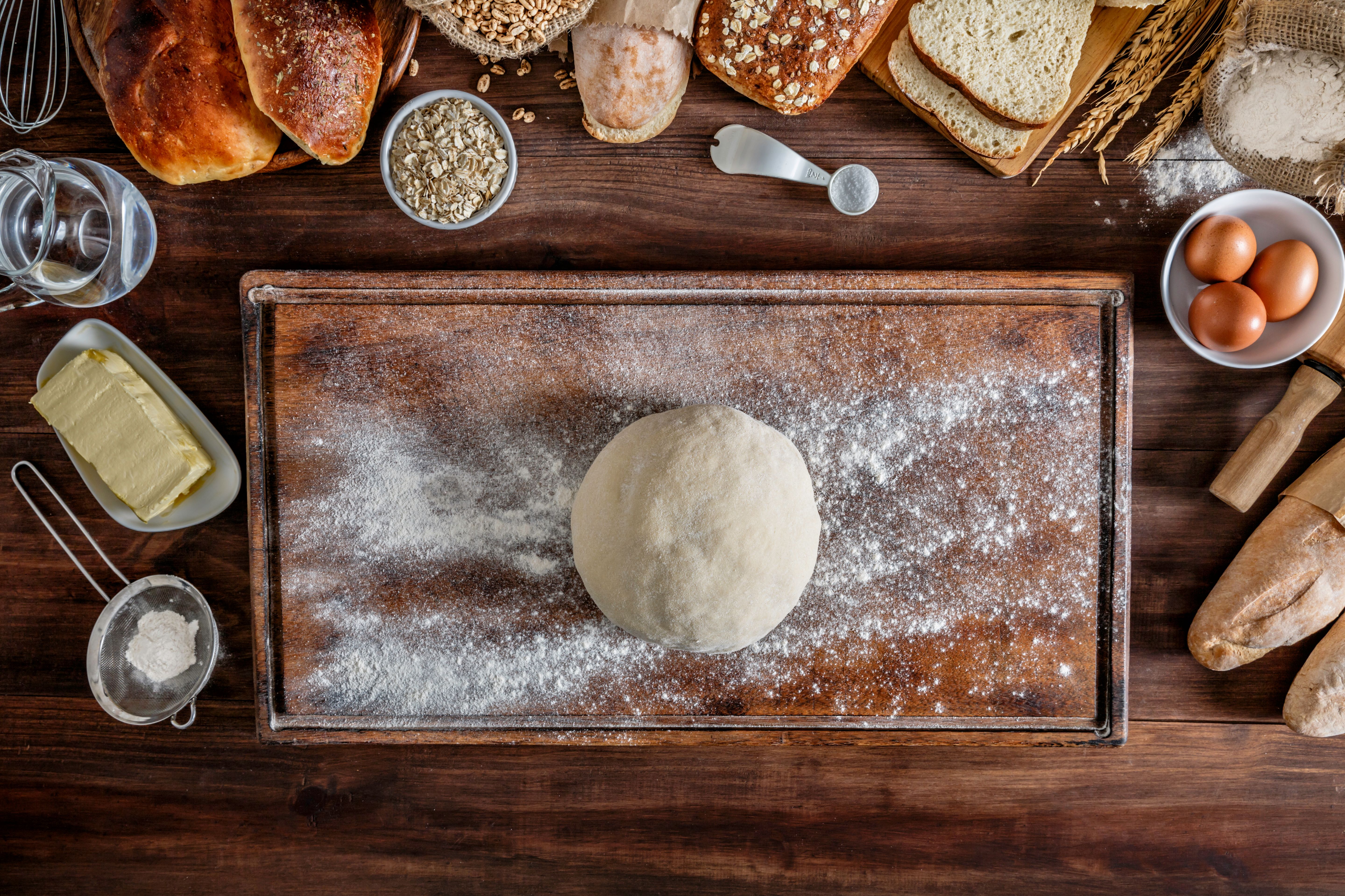 Frame of ingredients for bread preparation with a rustic wooden on the middle Frame of ingredients for bread preparation with a rustic wooden on the middle